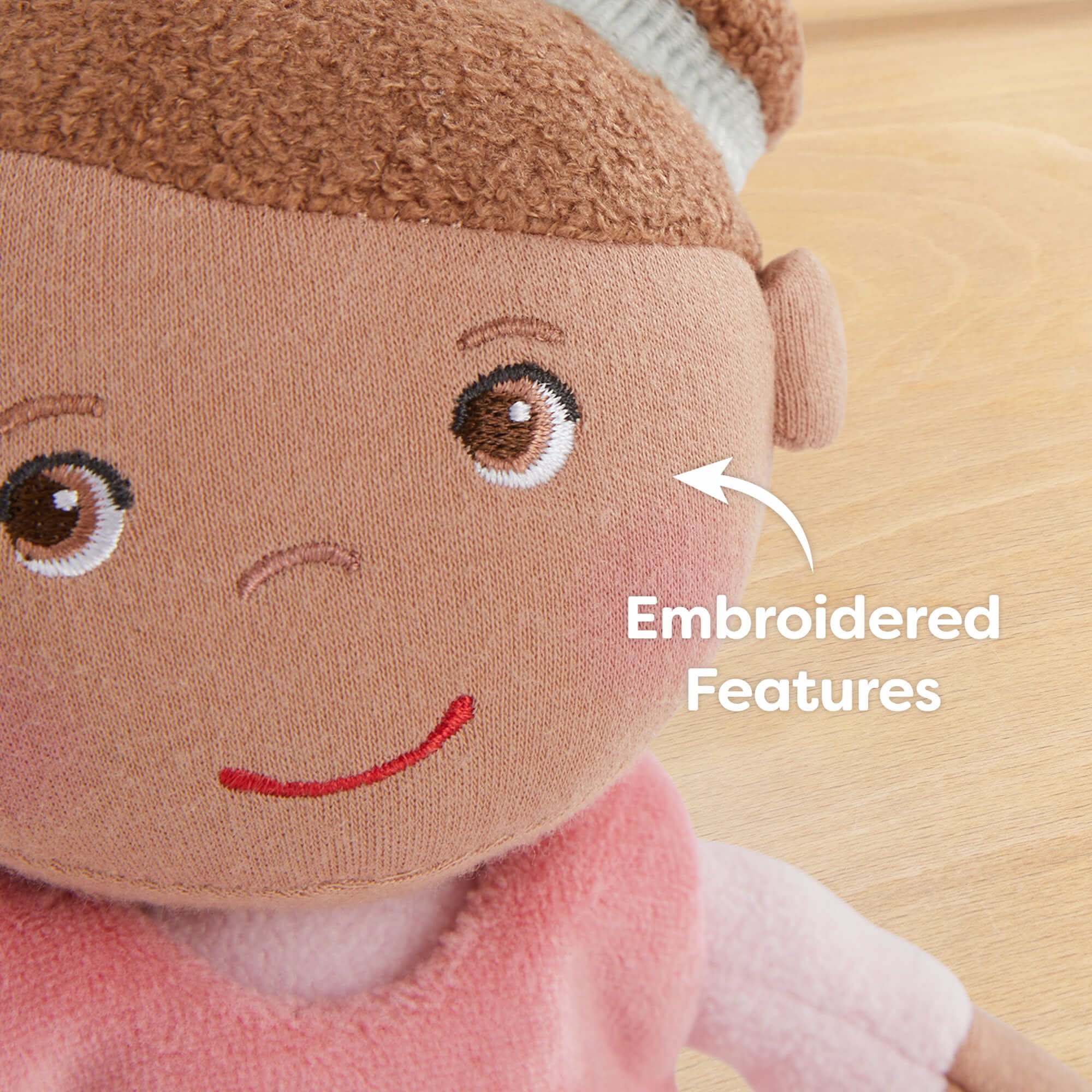 Close-up of a plush toy with embroidered features on a wooden surface