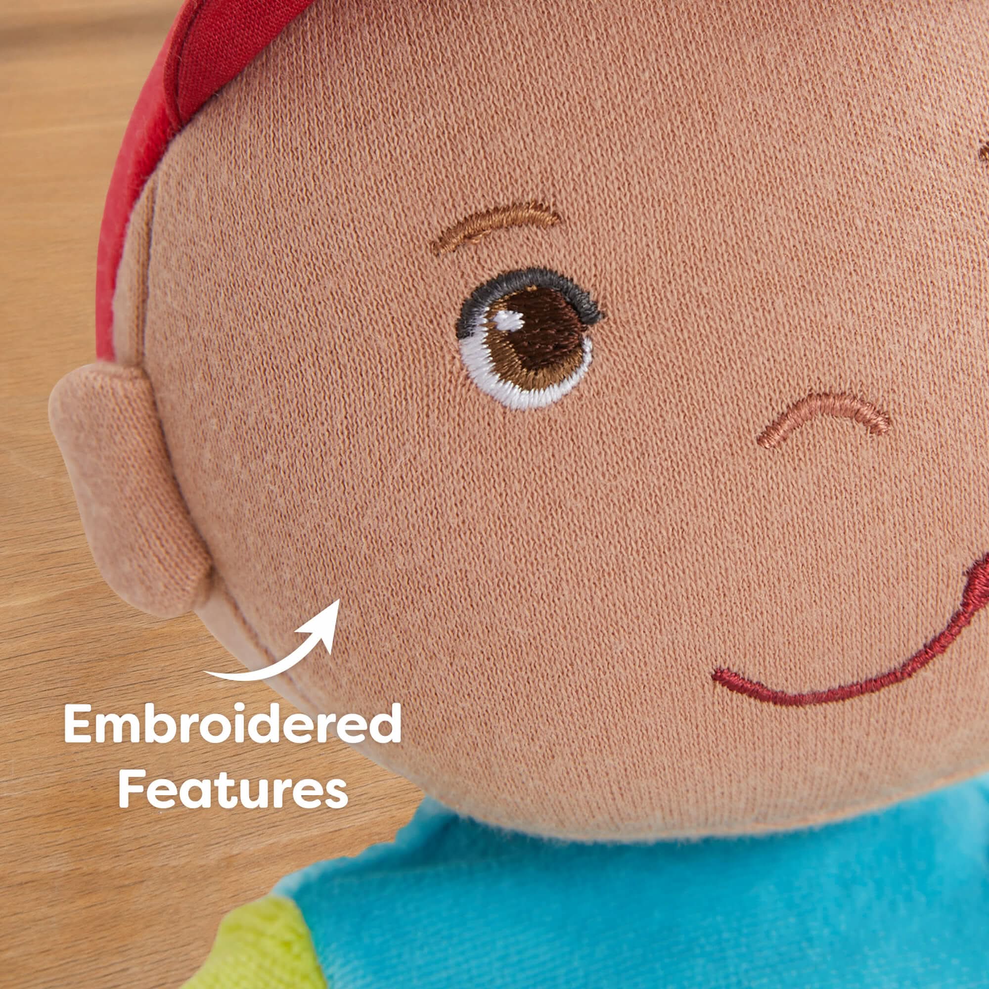 Close-up of a plush toy with embroidered features on a wooden surface