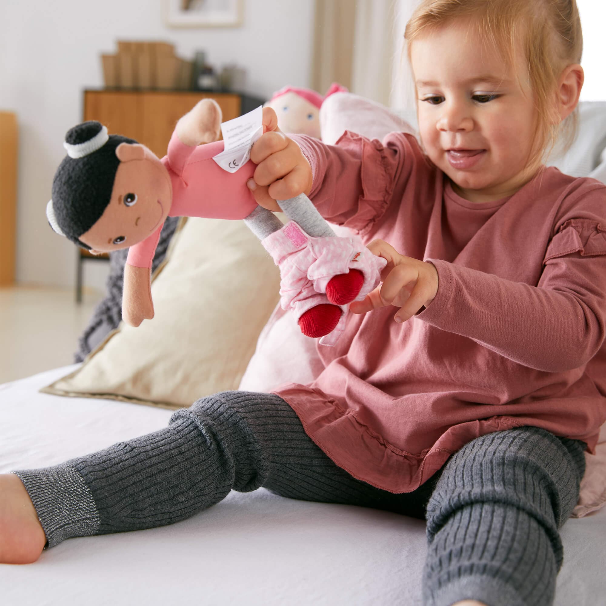 Child playing with a plush toy on a bed
