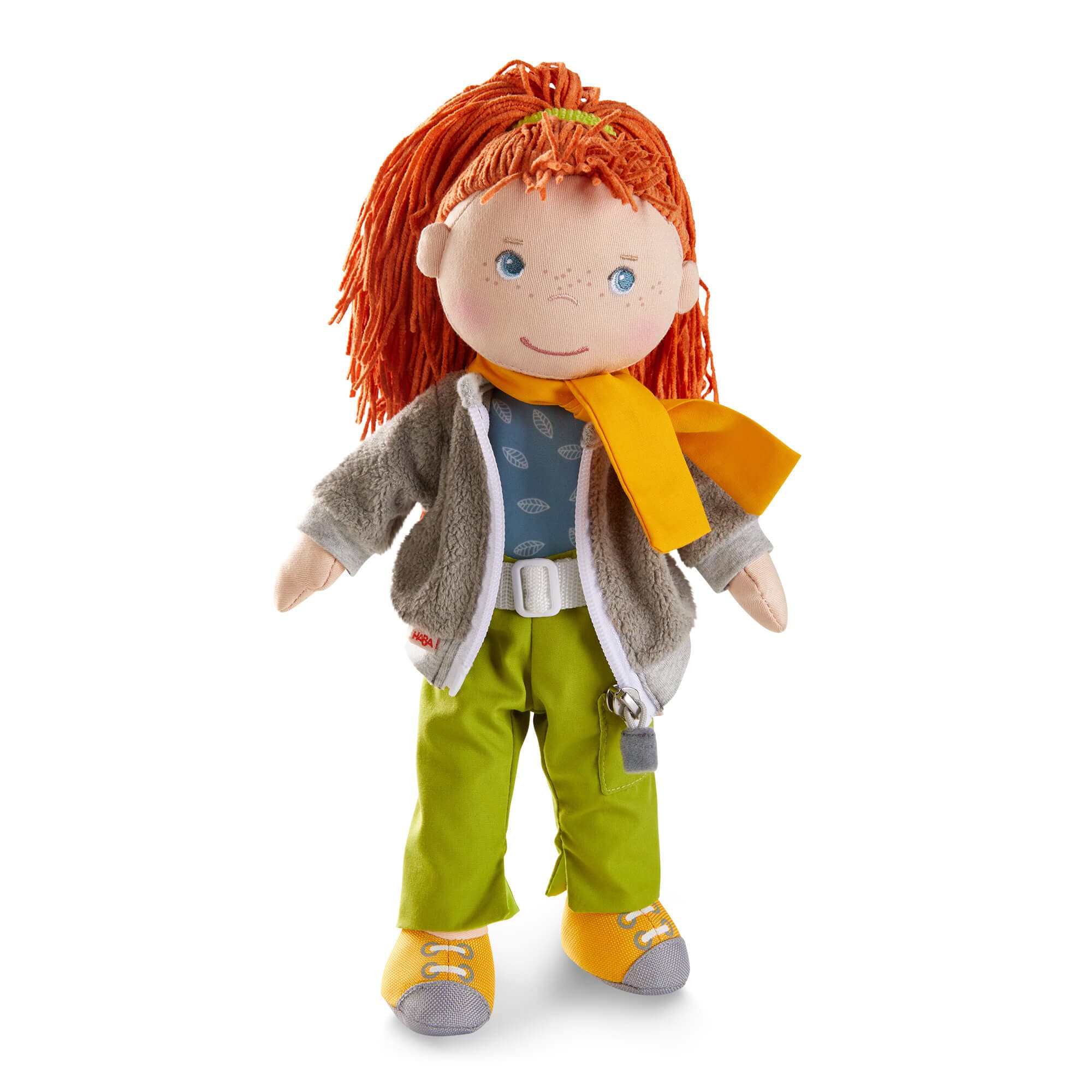 Toy doll with red hair, wearing a yellow scarf, gray jacket, blue shirt, green pants, and yellow shoes on a white background.