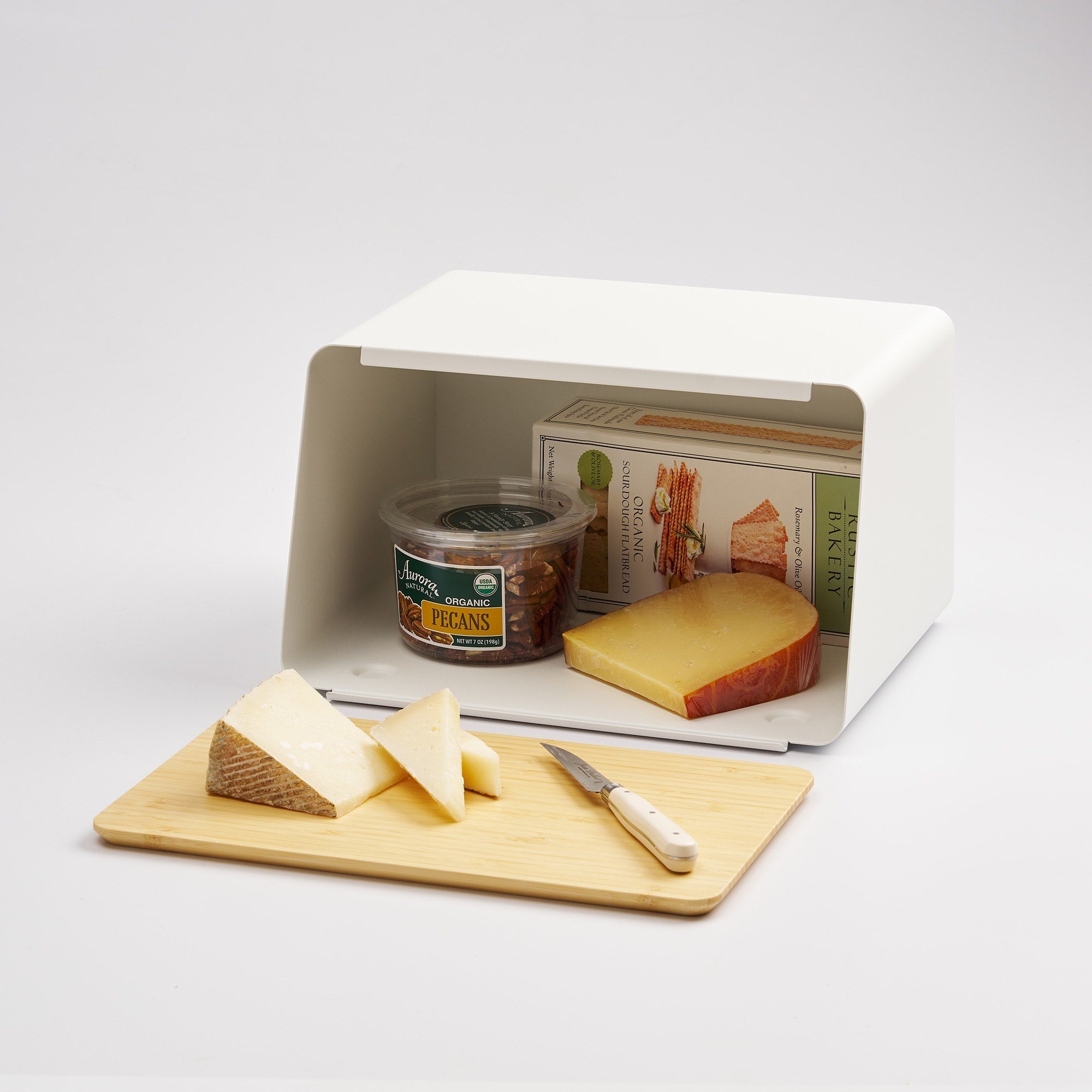 Cheese display with a small refrigerator, cutting board, knife, and cheese slices on a white background