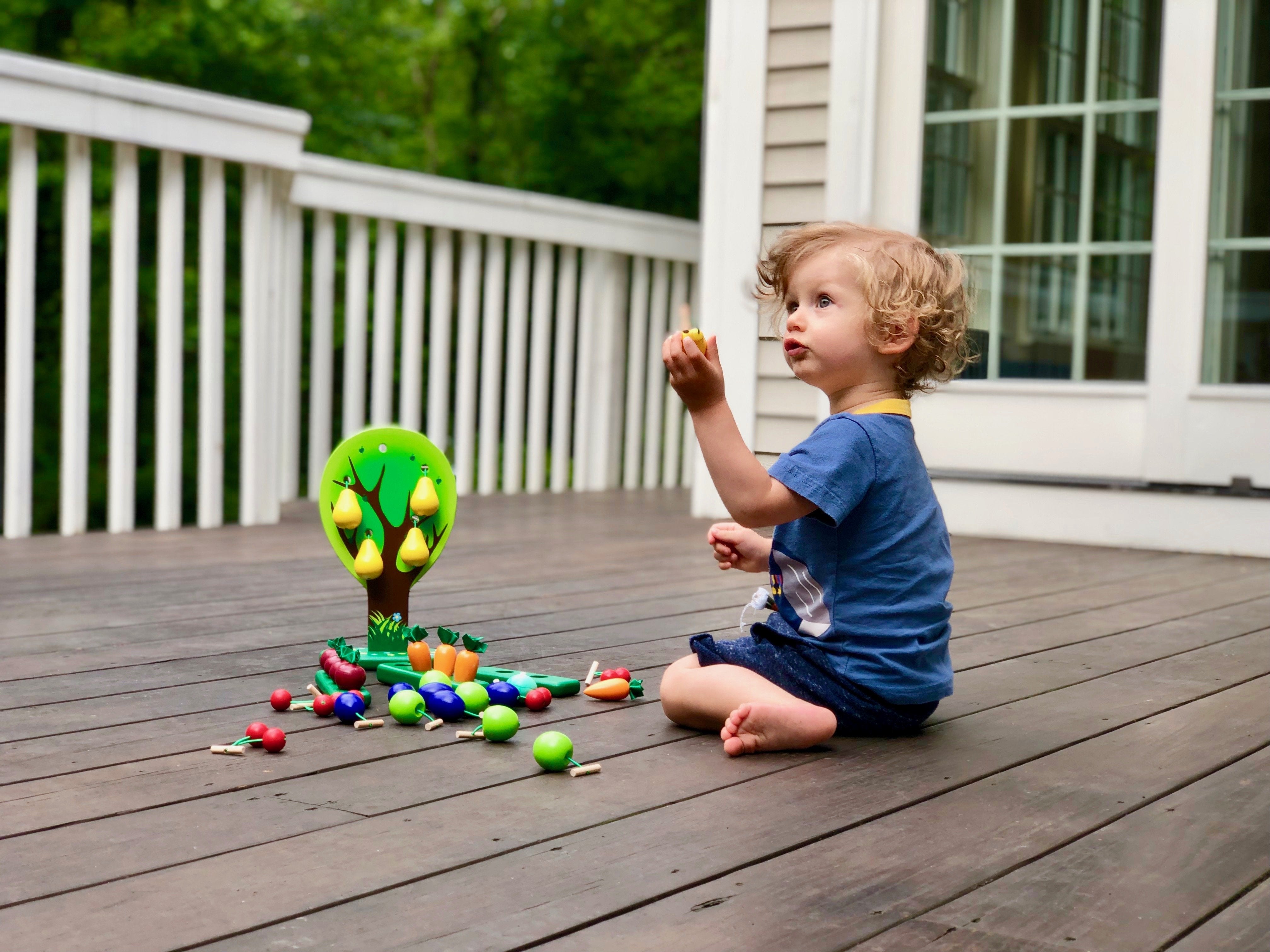 Child playing with colorful toys on a wooden deck