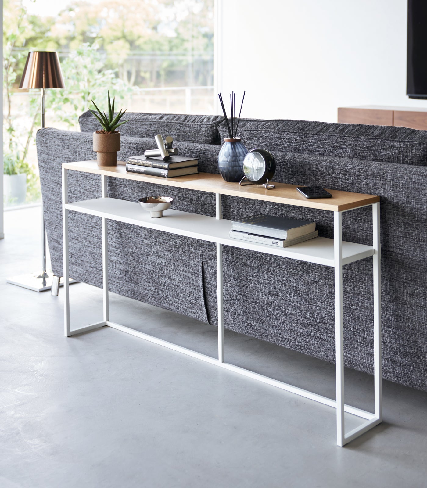 Console table with decorative items in front of a gray sofa in a modern living room.