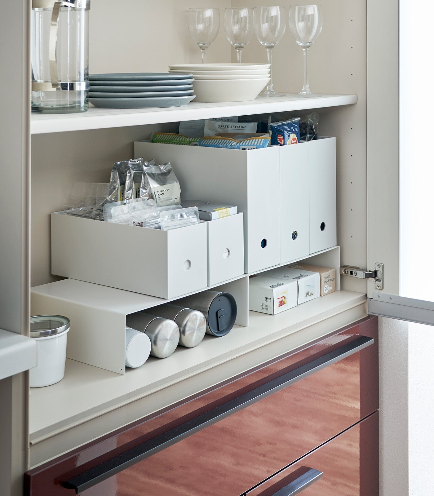 Open kitchen cabinet with organized shelves and storage boxes.