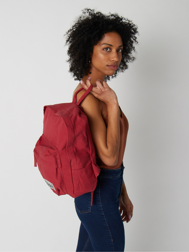 Woman carrying a red backpack on a plain background