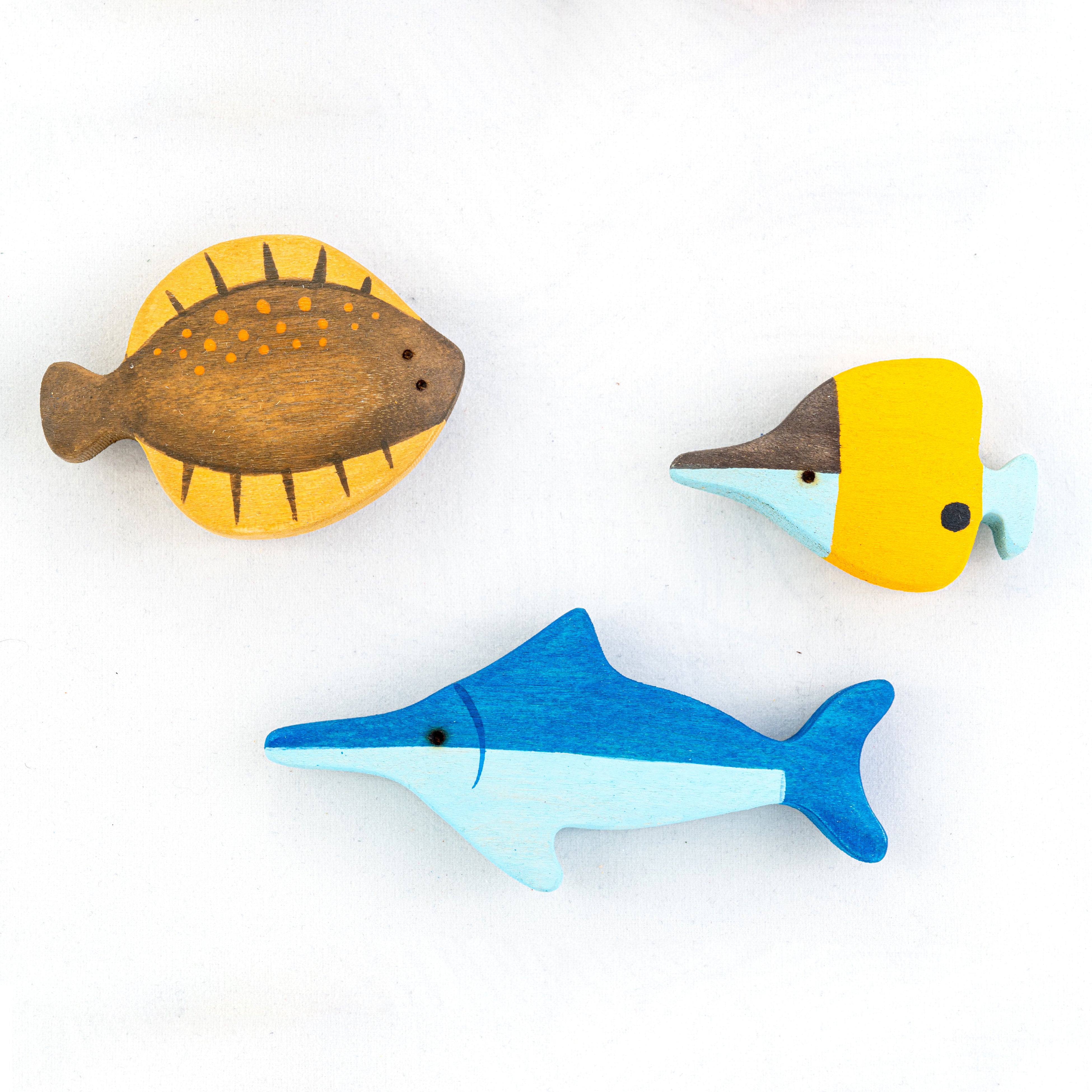 Three wooden fish toys on a white background