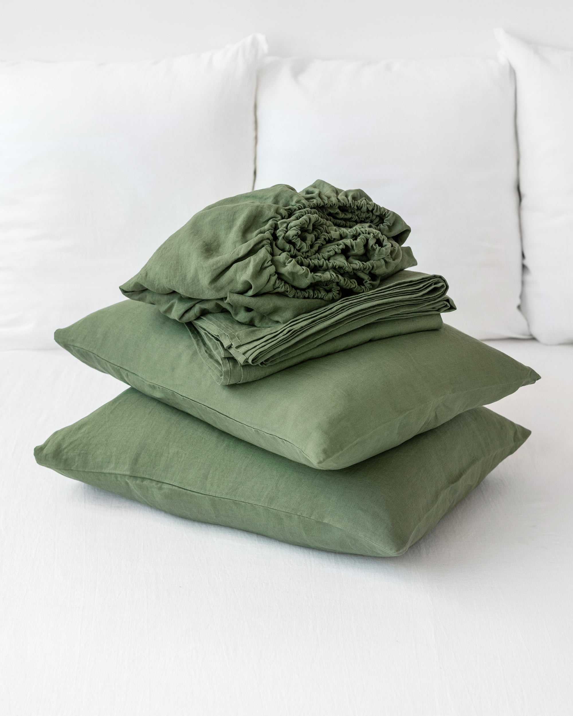 Green bedding set including a duvet and two pillows on a white couch.