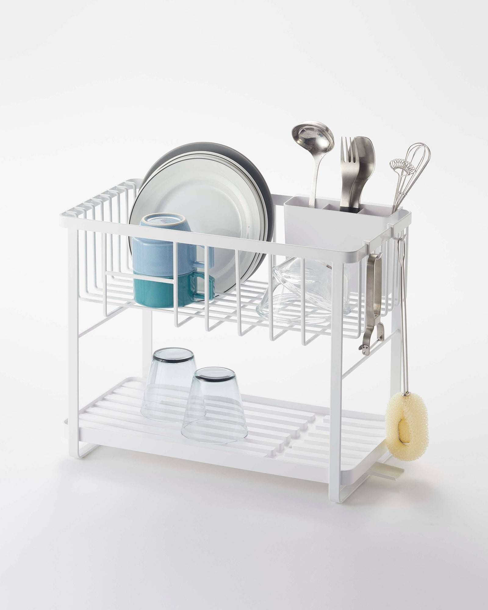 White dish rack with utensils and dishes on a white background