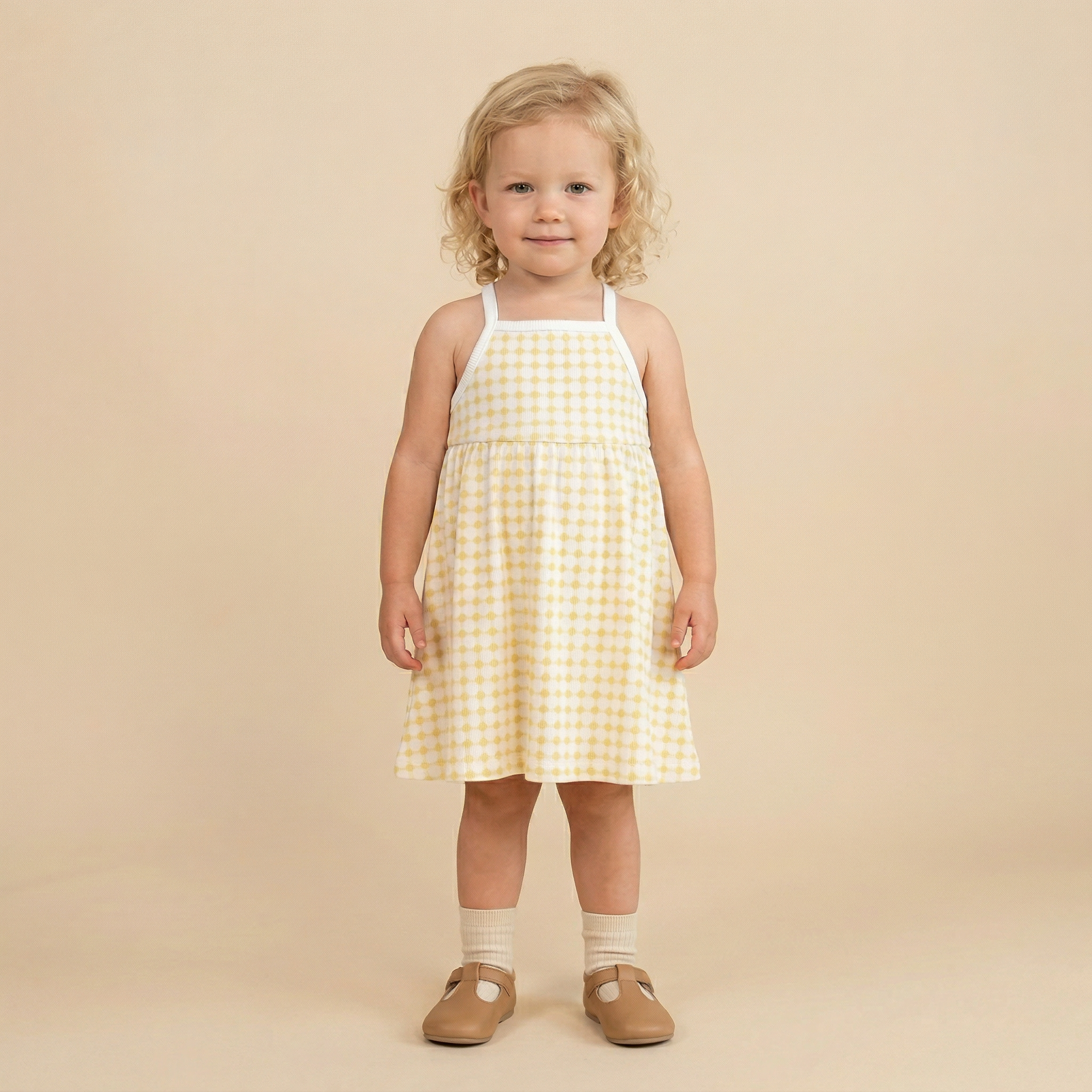 Young girl wearing a yellow checkered dress on a beige background