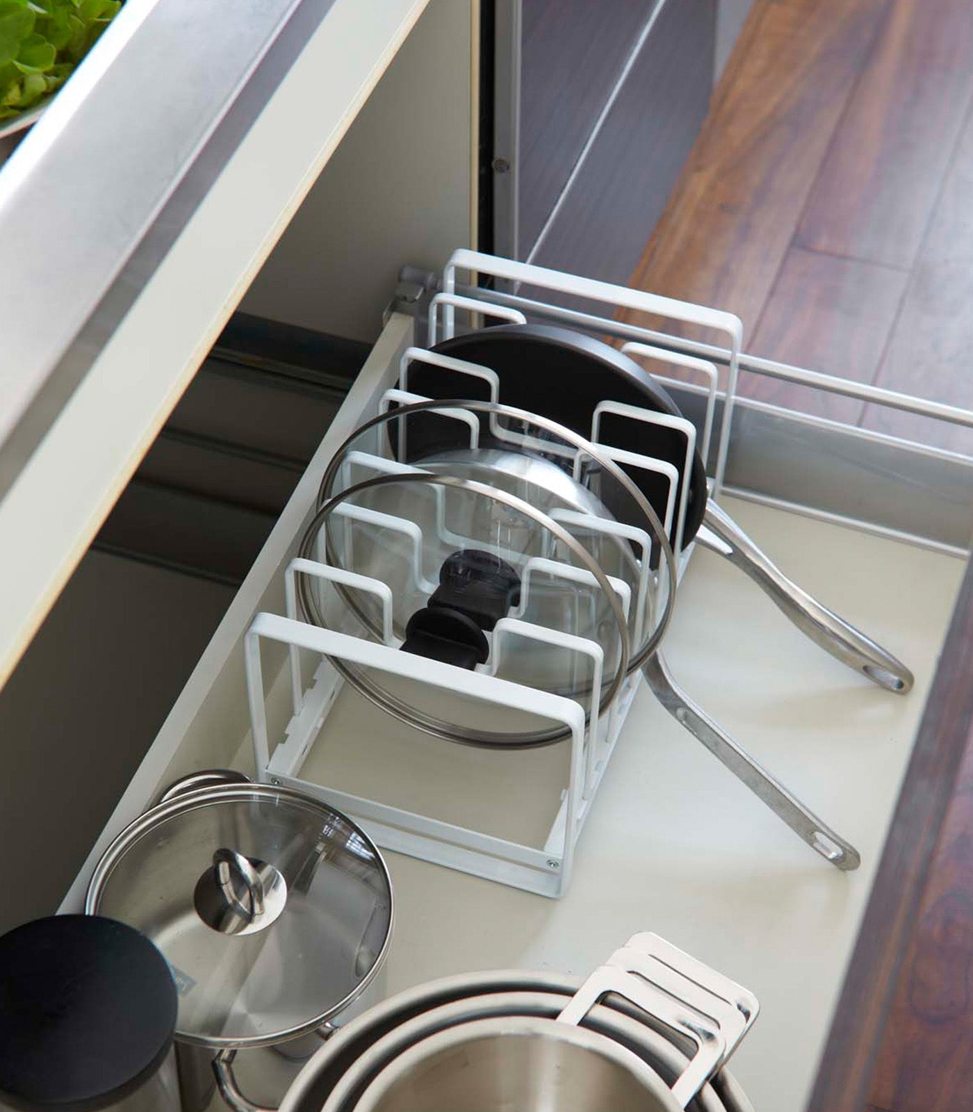 Kitchen drawer organizer with pots and pans inside a kitchen cabinet.