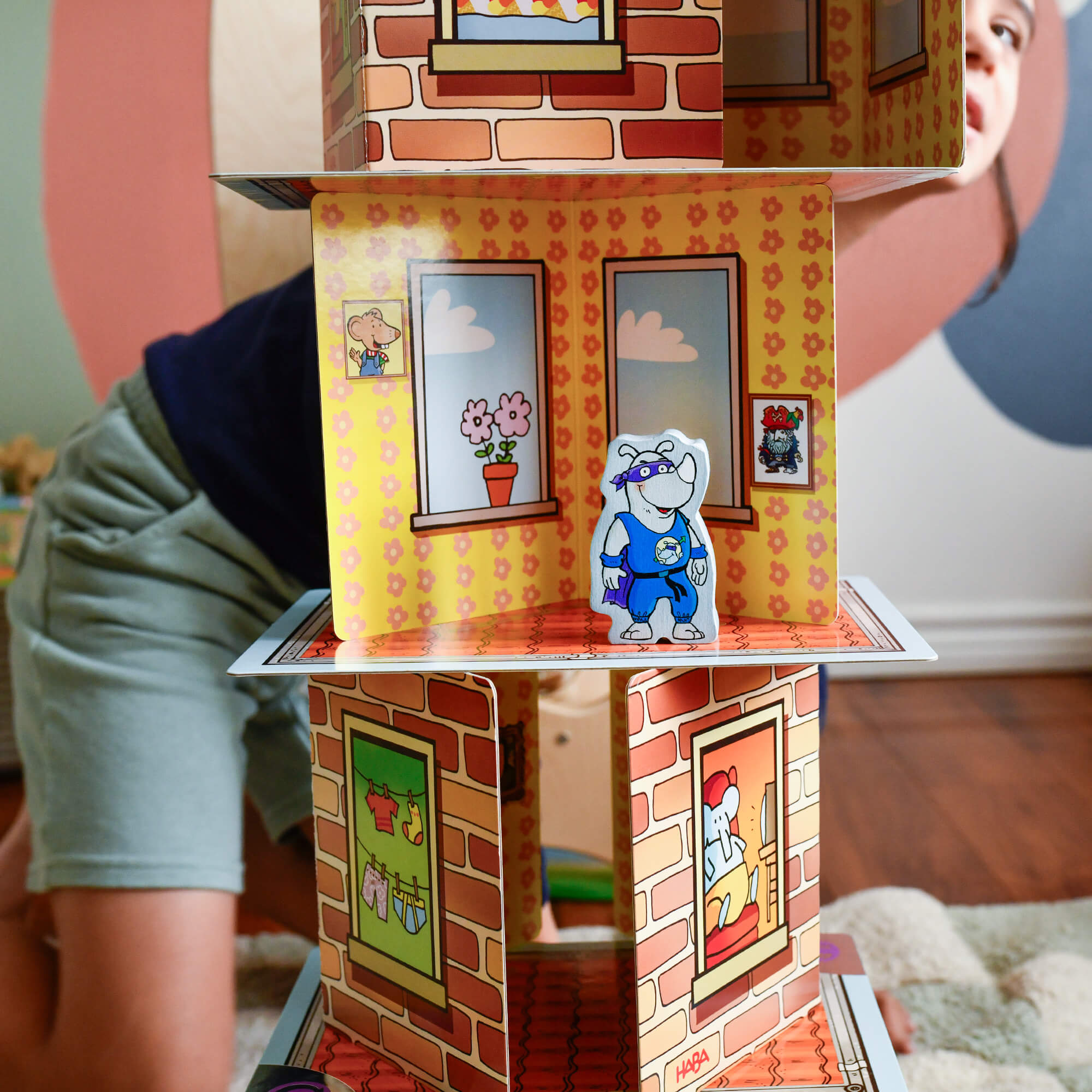 Child playing with a colorful cardboard house toy