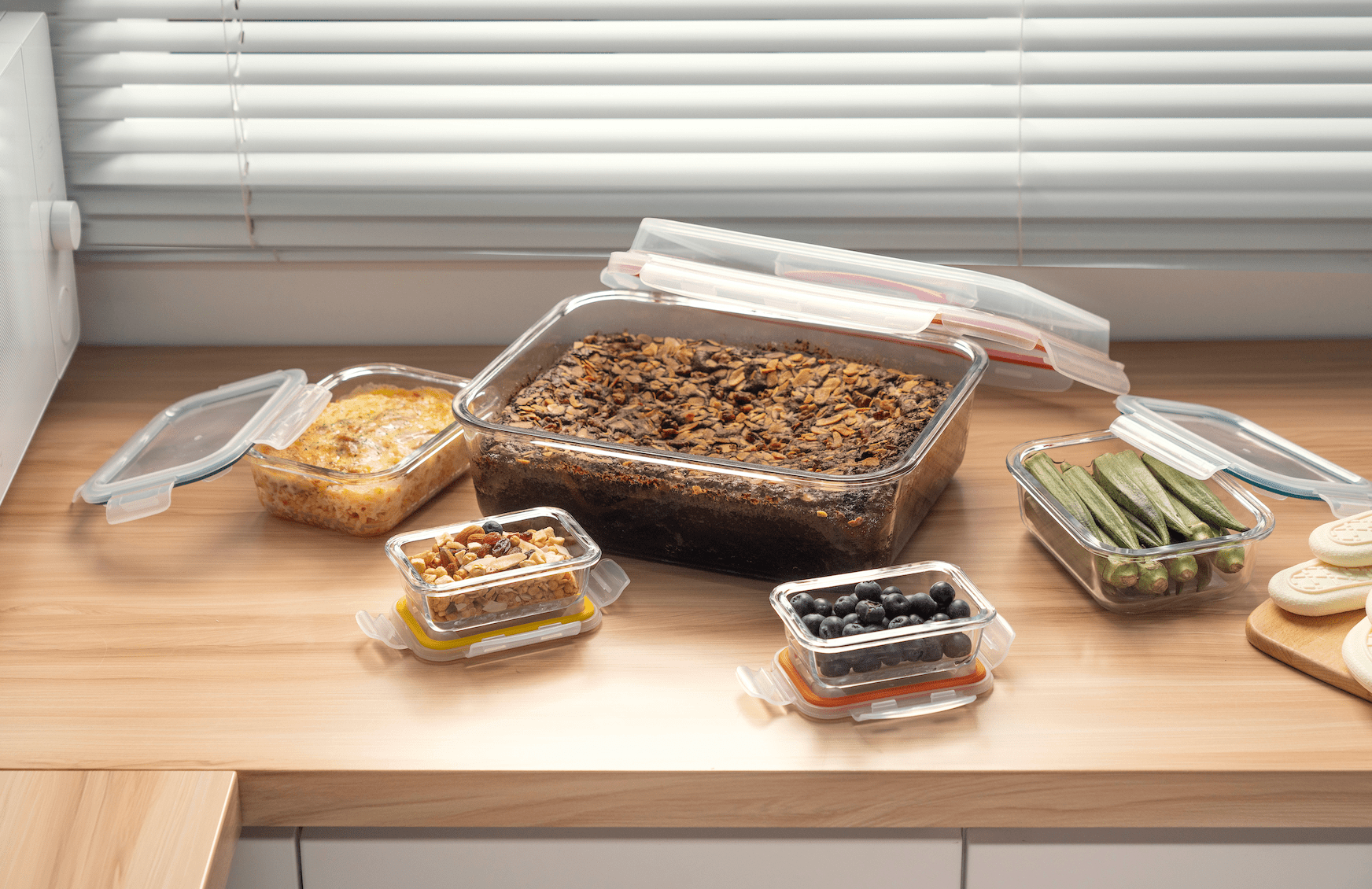 Set of glass food containers with lids on a wooden countertop.