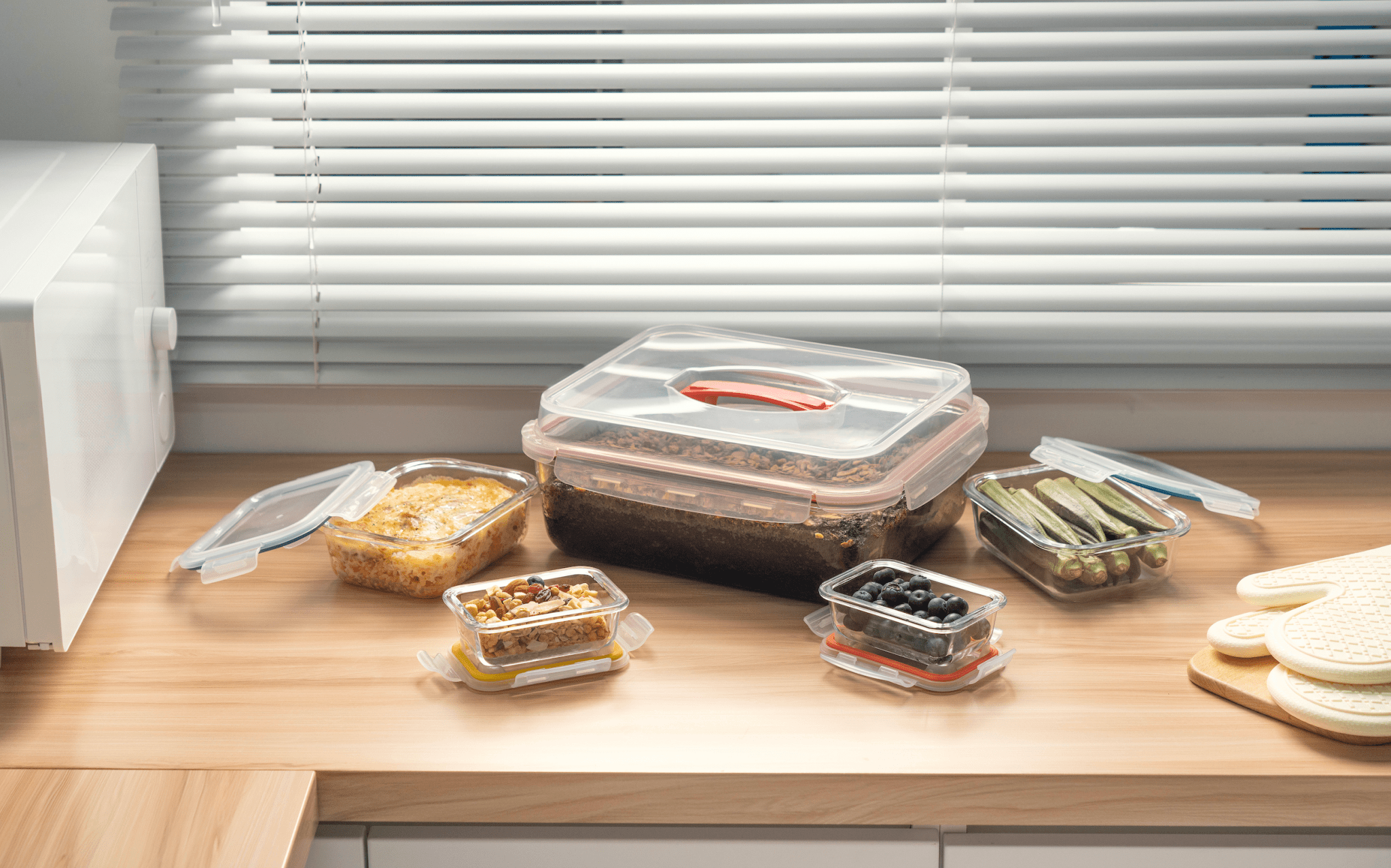 Set of food containers on a wooden surface with blinds in the background