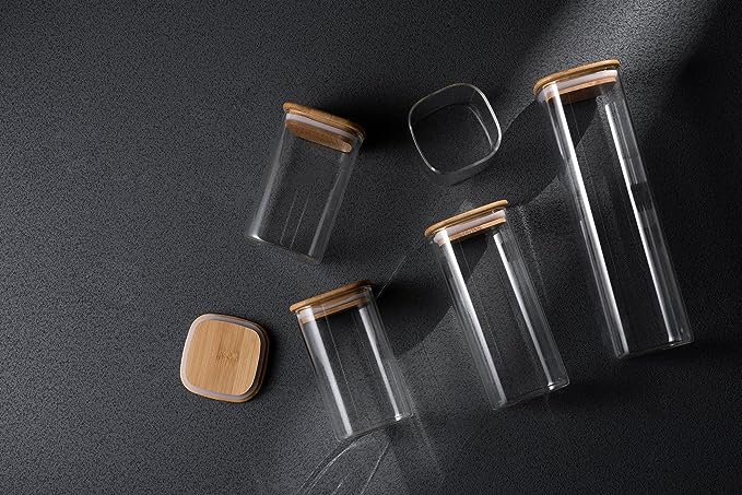Set of glass jars with wooden lids on a dark surface