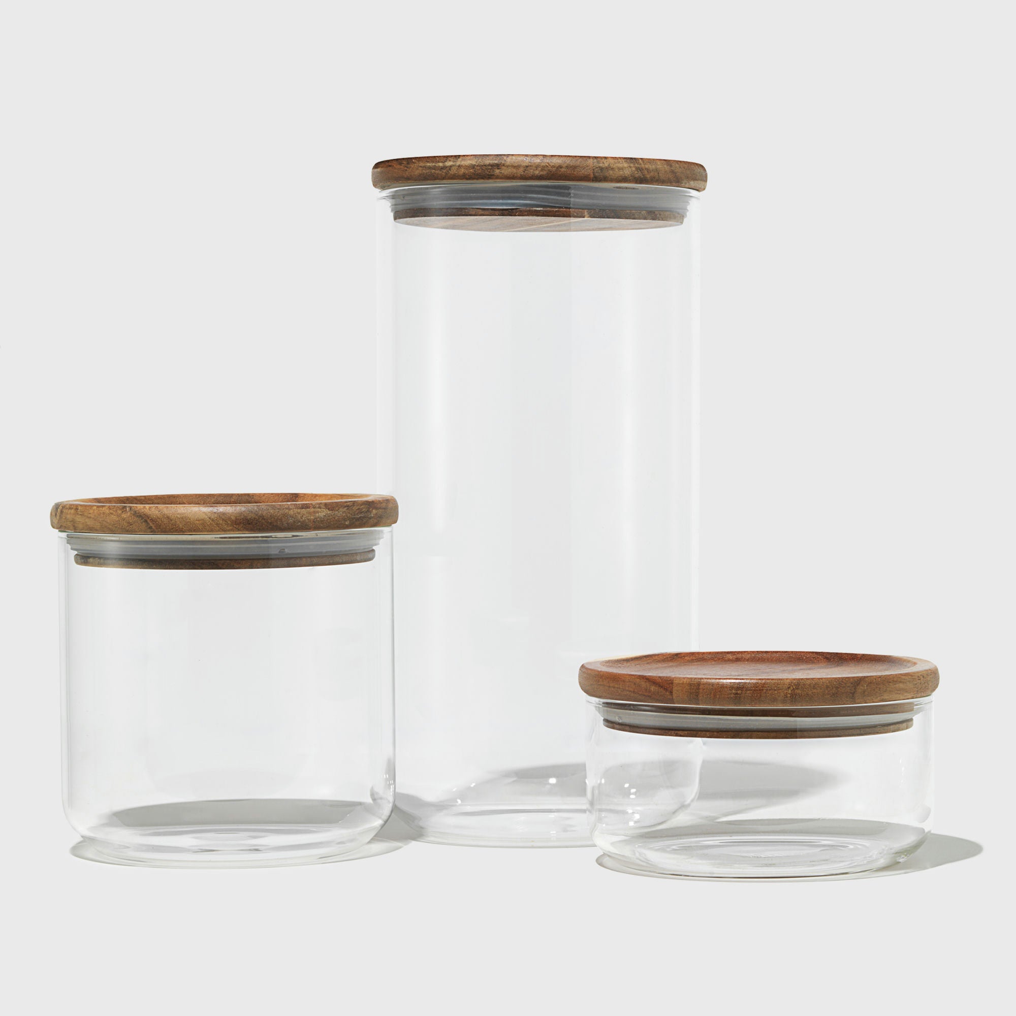 Three glass jars with wooden lids on a white background