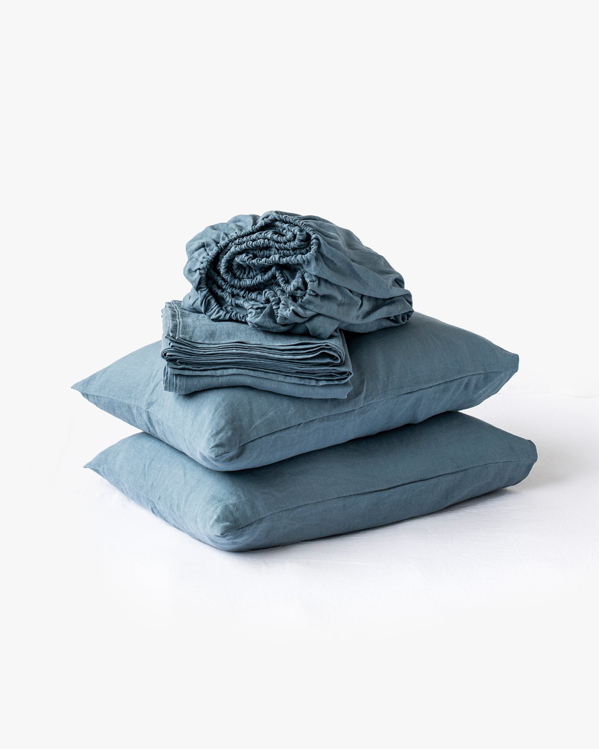 Blue bedding set with pillows and a folded blanket on a white background