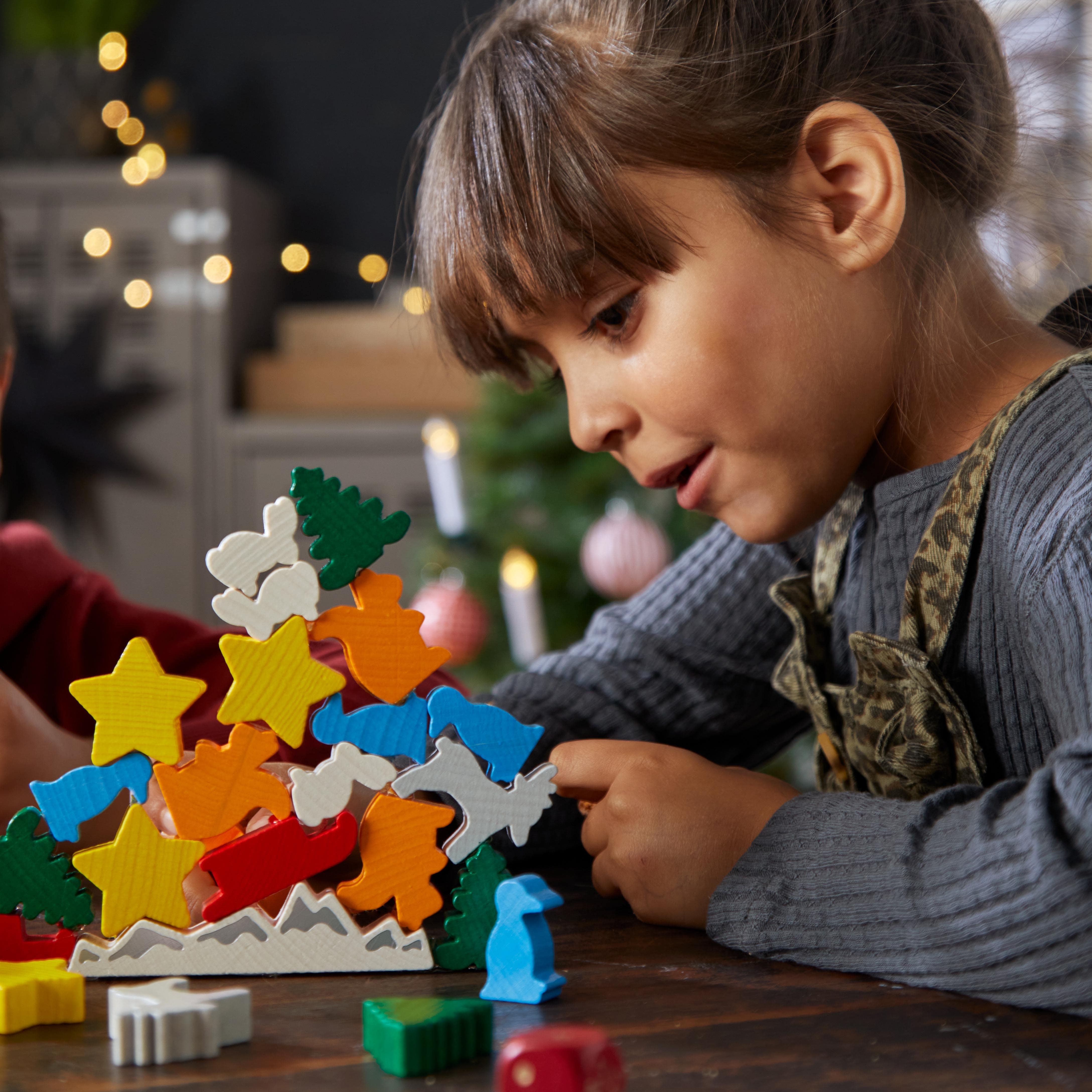 Child playing with colorful wooden building blocks on a table.
