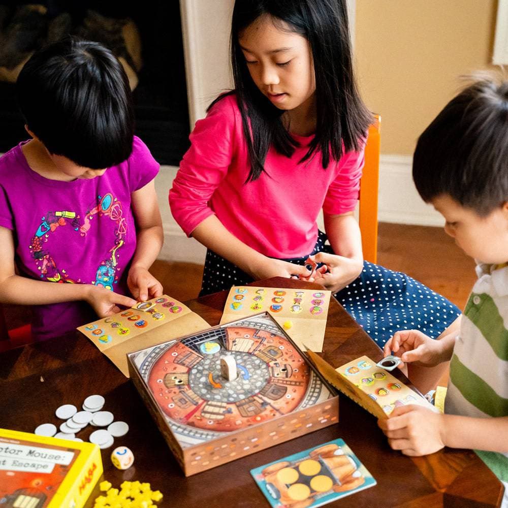 Three children playing a board game together on a wooden table.