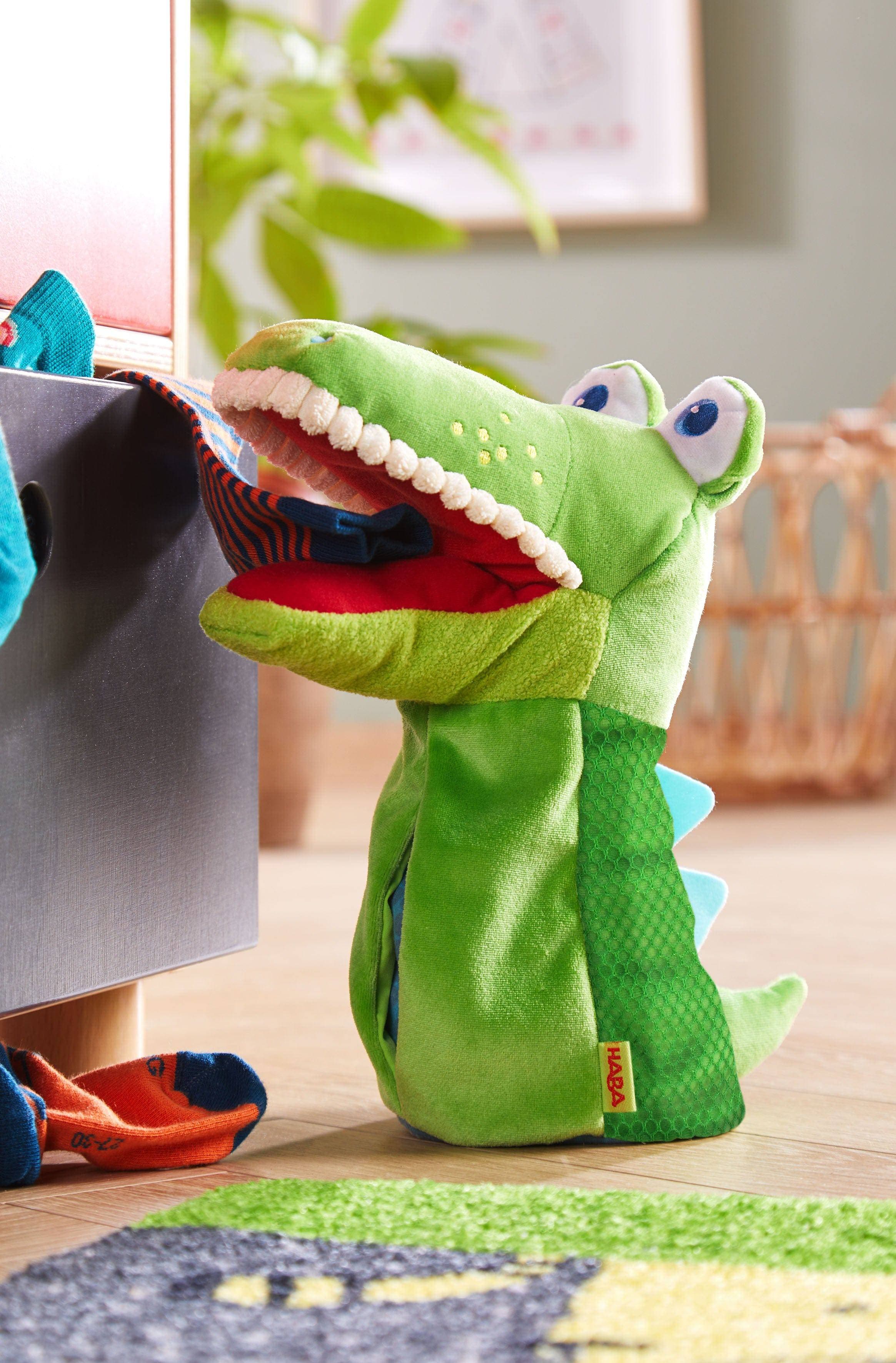 Green dinosaur puppet with open mouth on a wooden floor