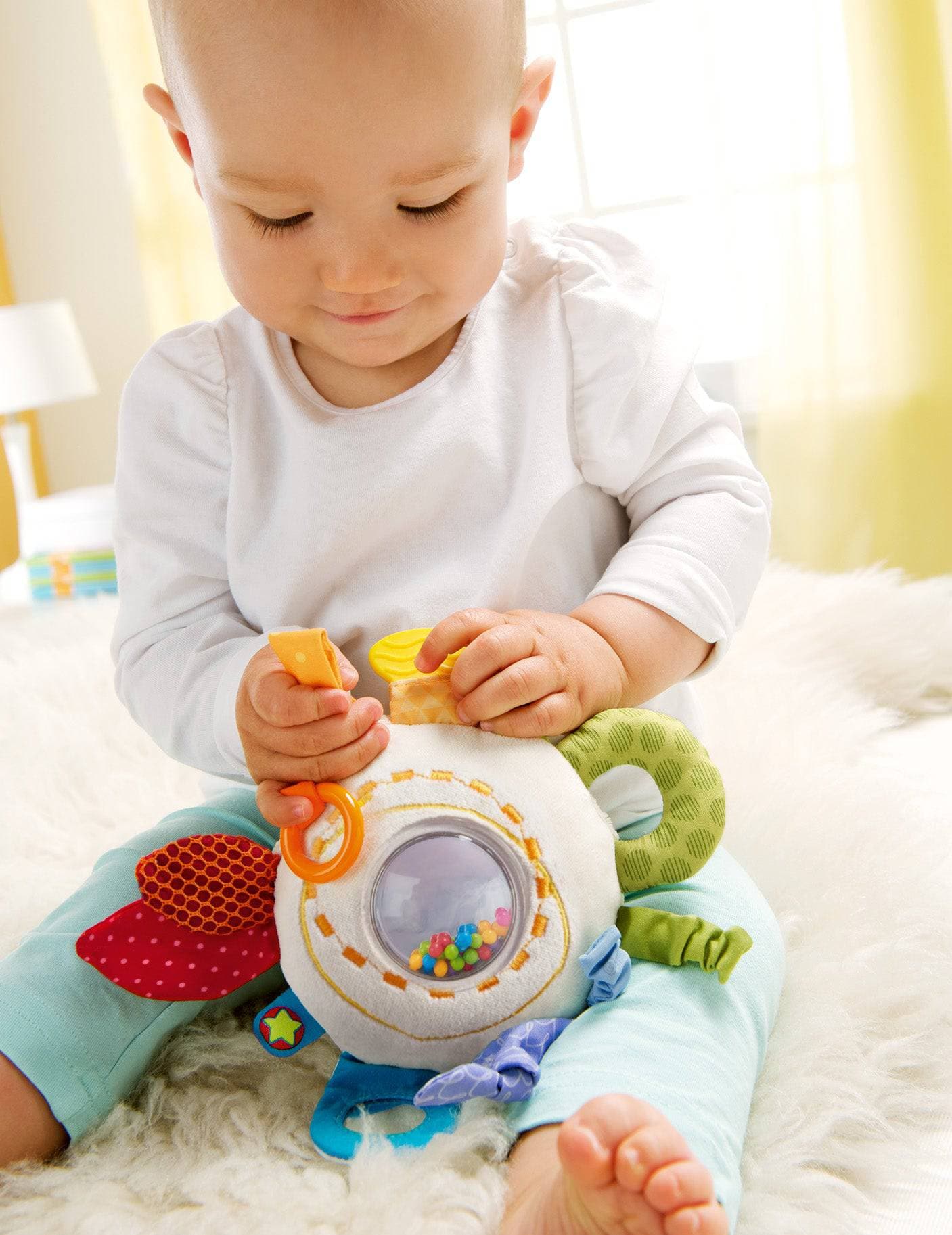 Baby playing with a colorful toy on a soft surface