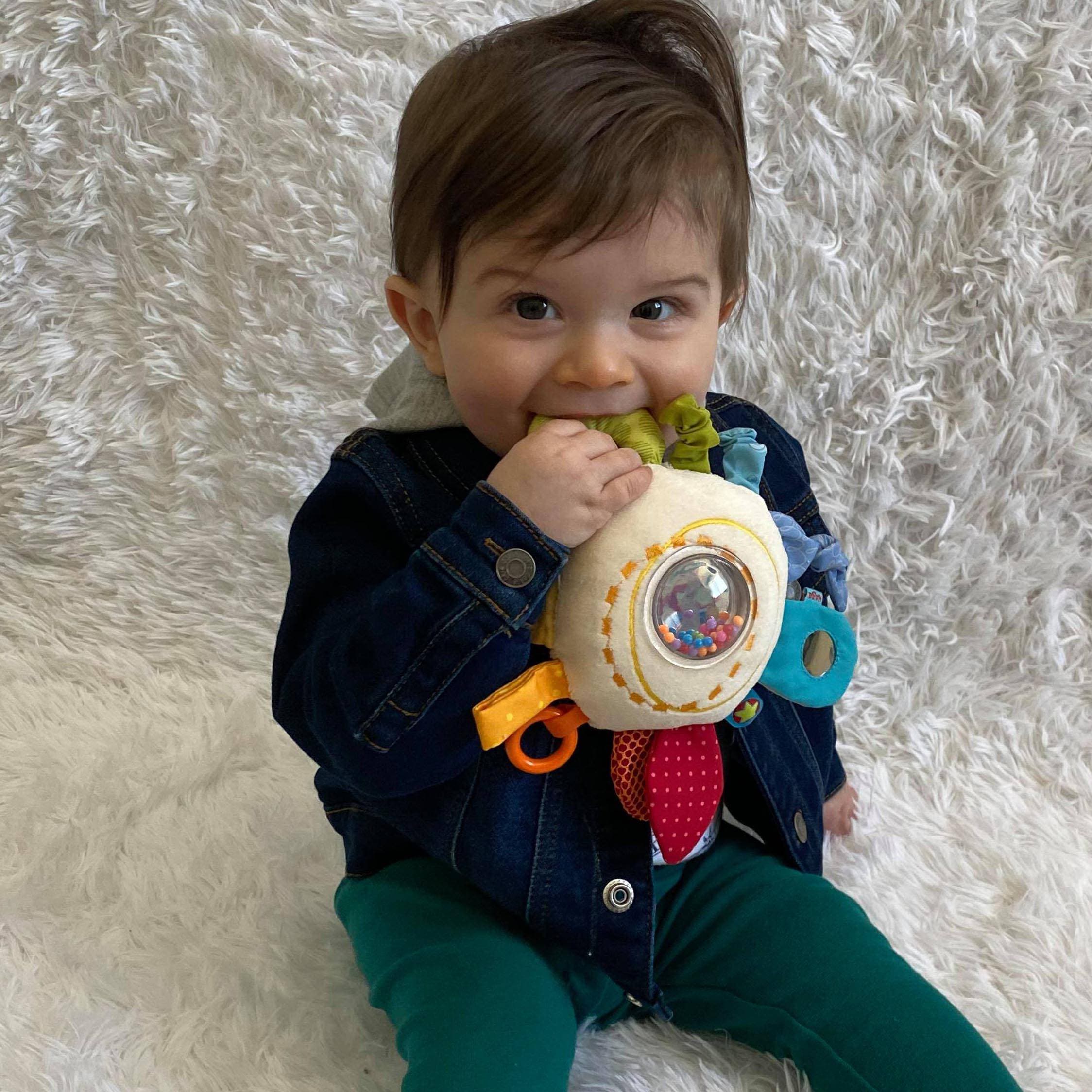 Child holding a colorful toy on a white fluffy surface