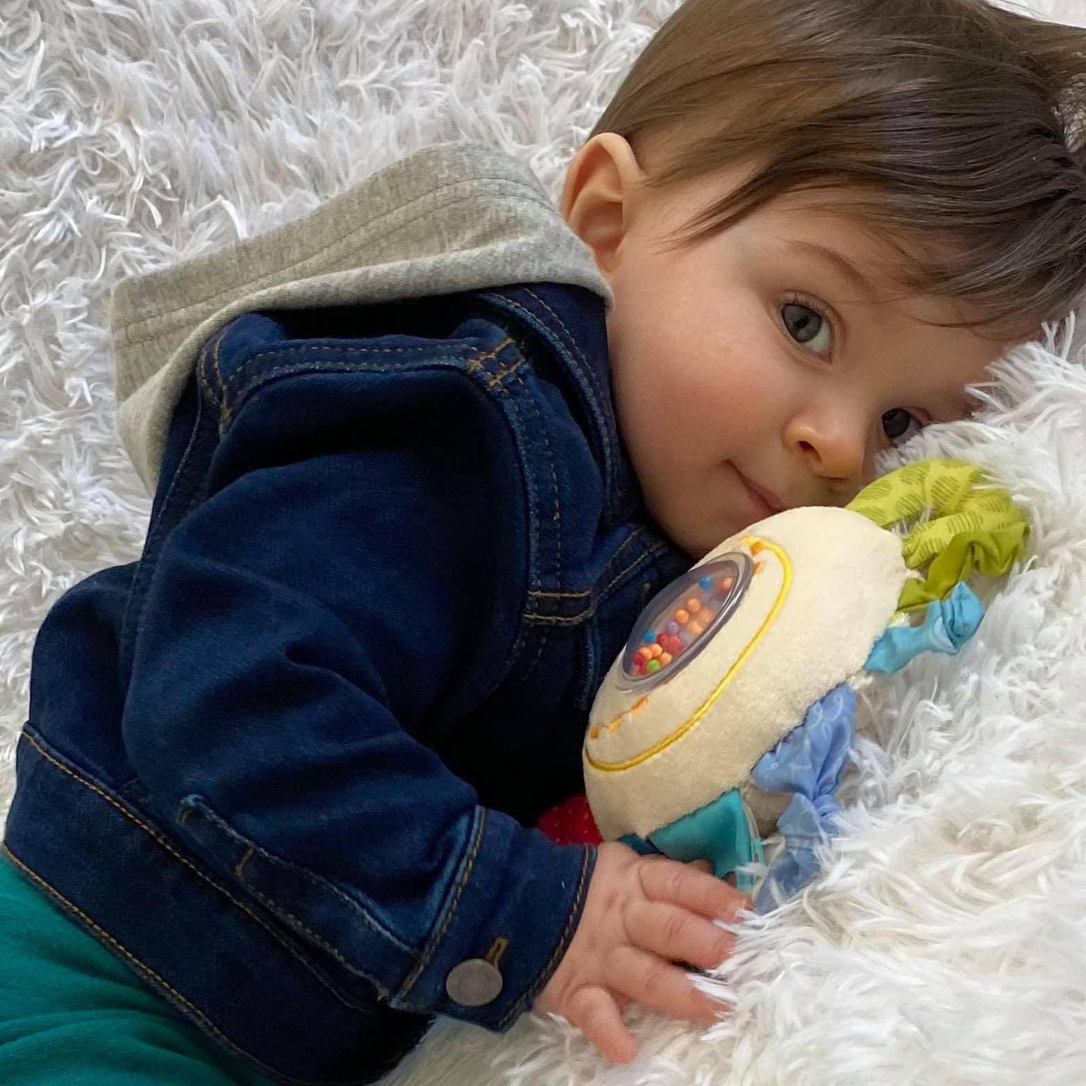 Child holding a colorful toy on a fluffy white surface