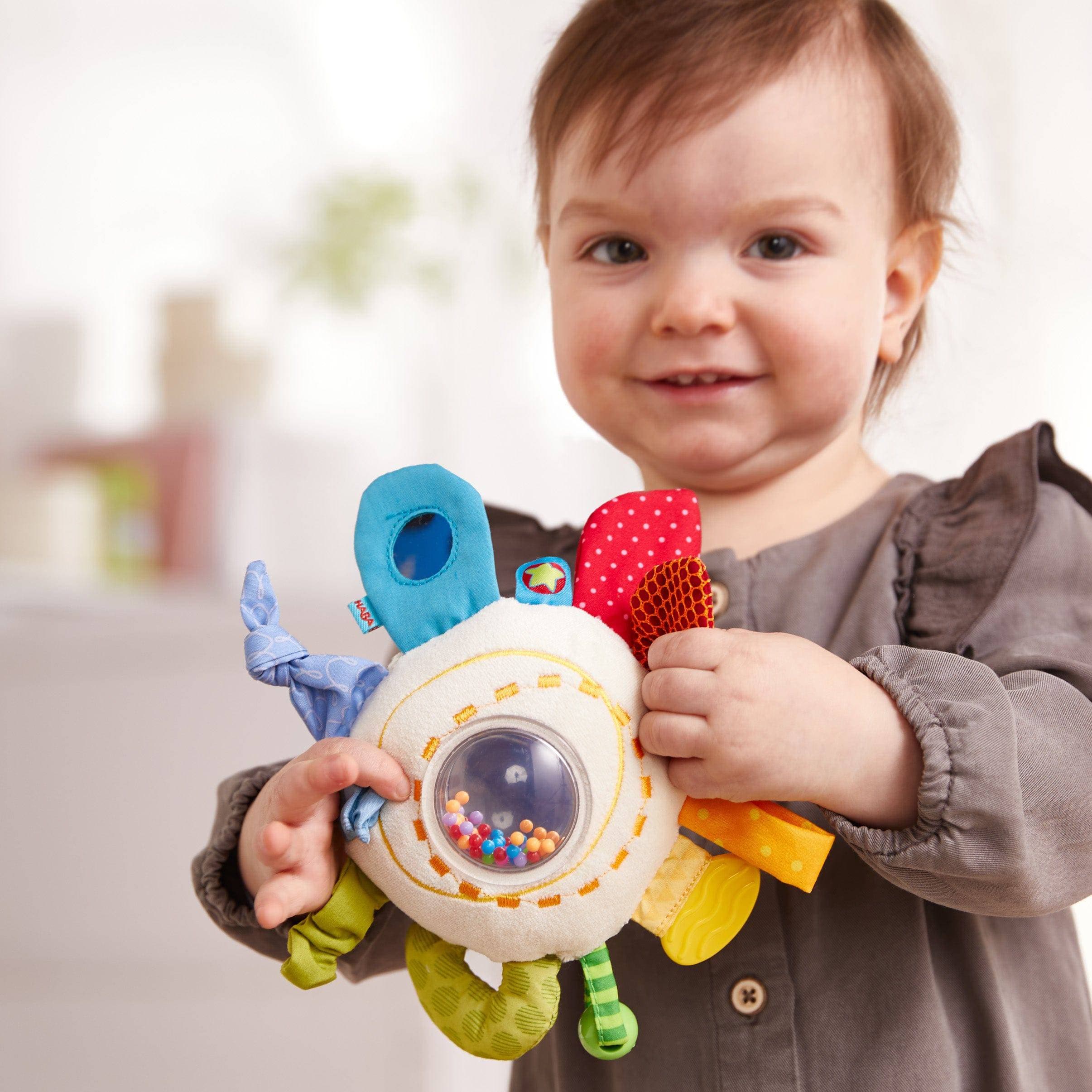 Child holding a colorful toy with various textures and shapes