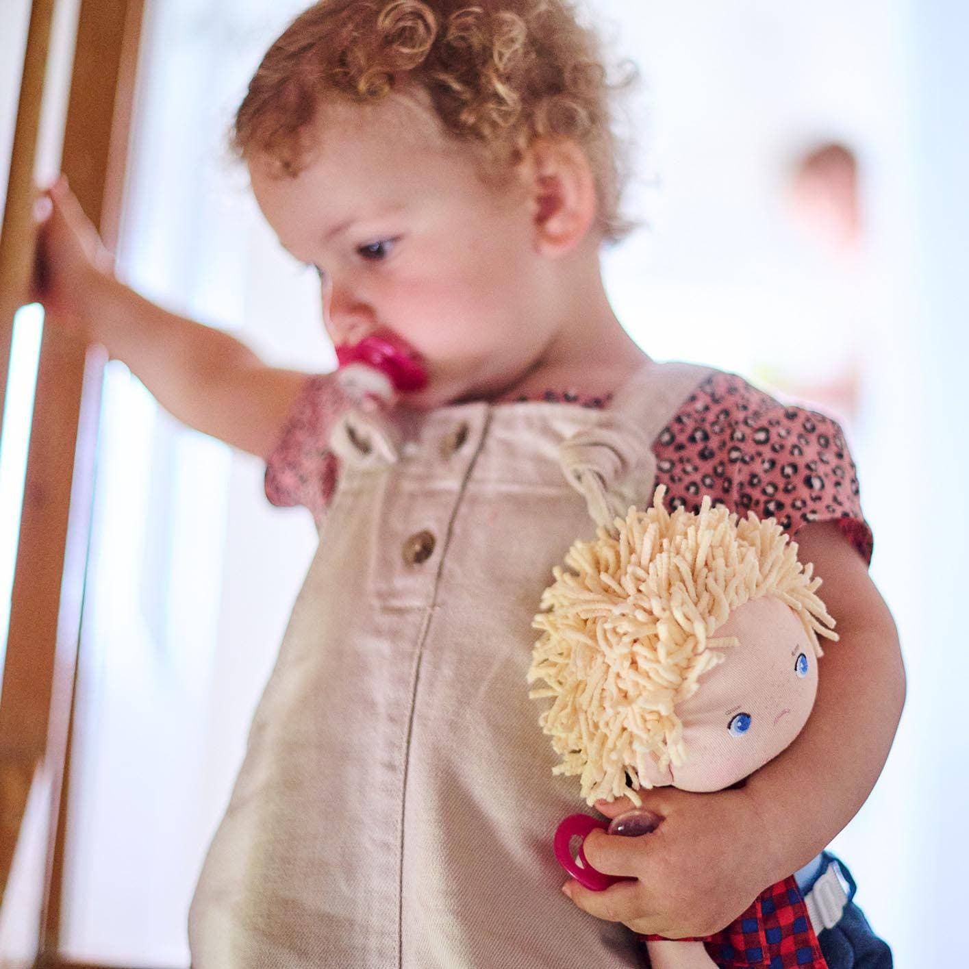 Child holding a doll with a blurred background