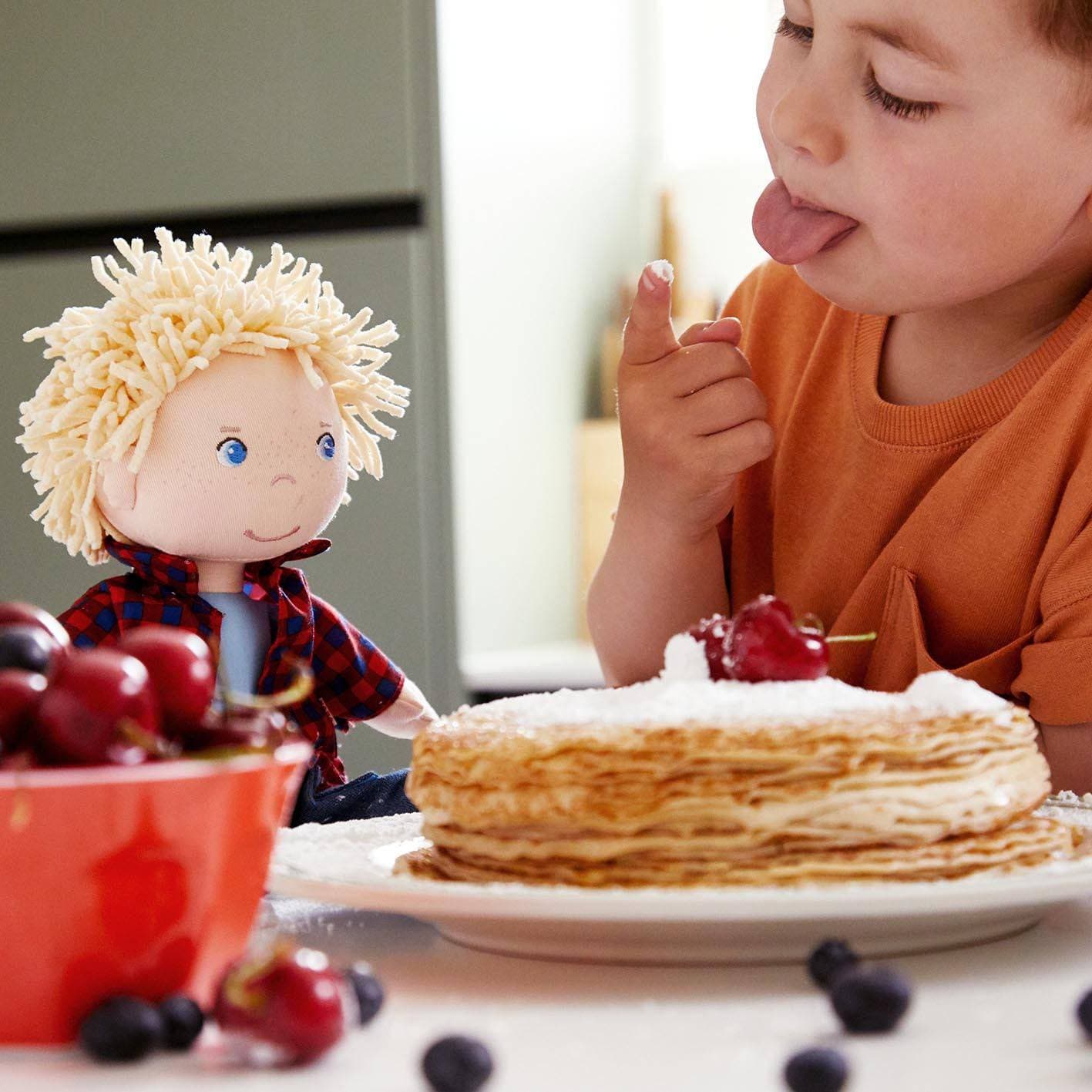 Child with a cake and doll on a table
