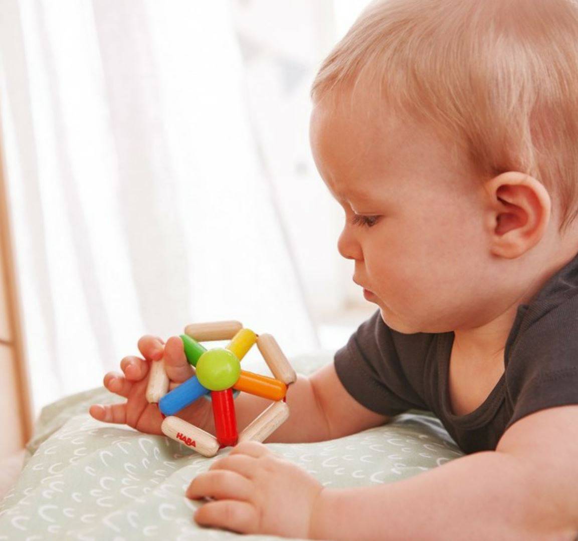 Baby playing with a colorful toy on a light surface