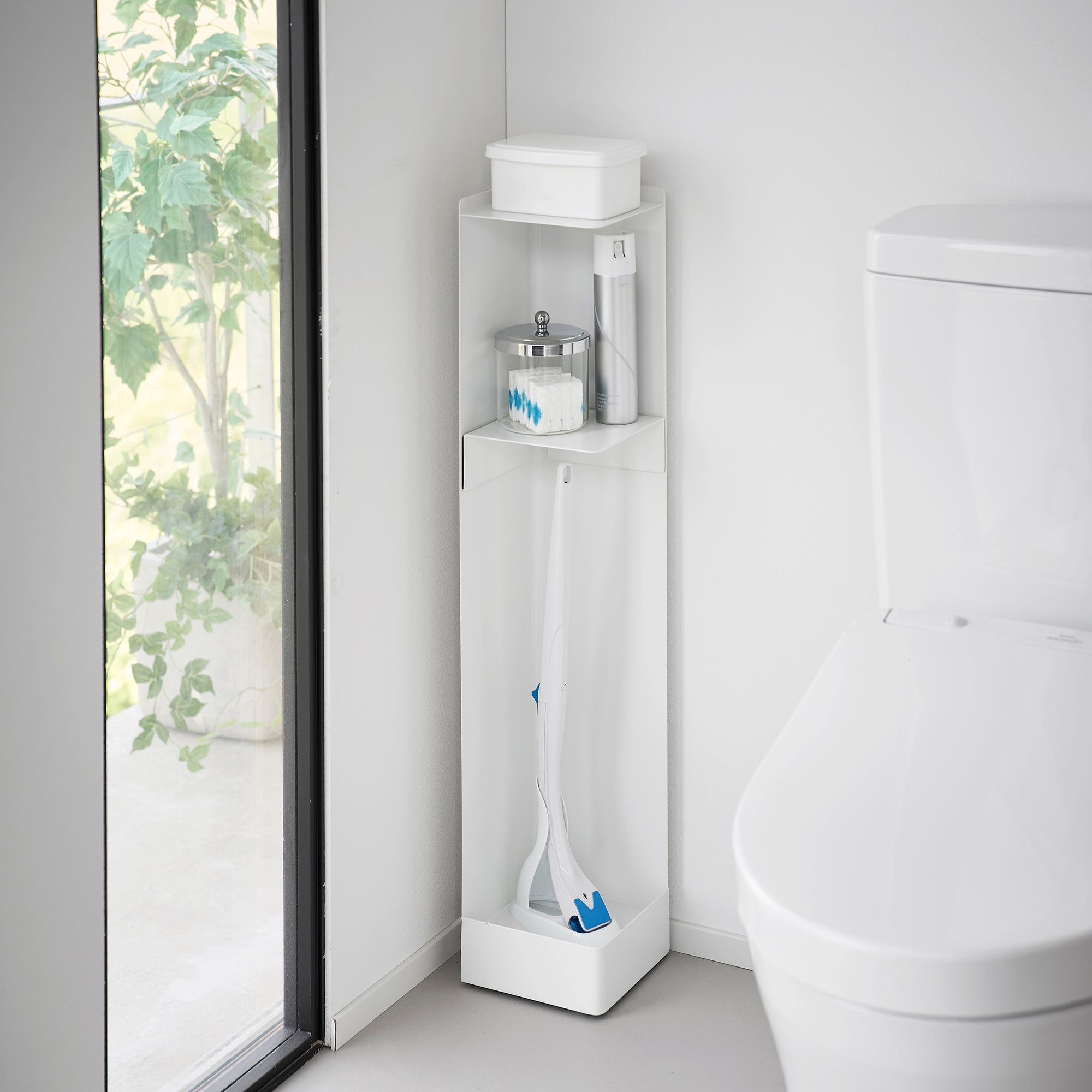 White corner cabinet with cleaning supplies in a bathroom setting