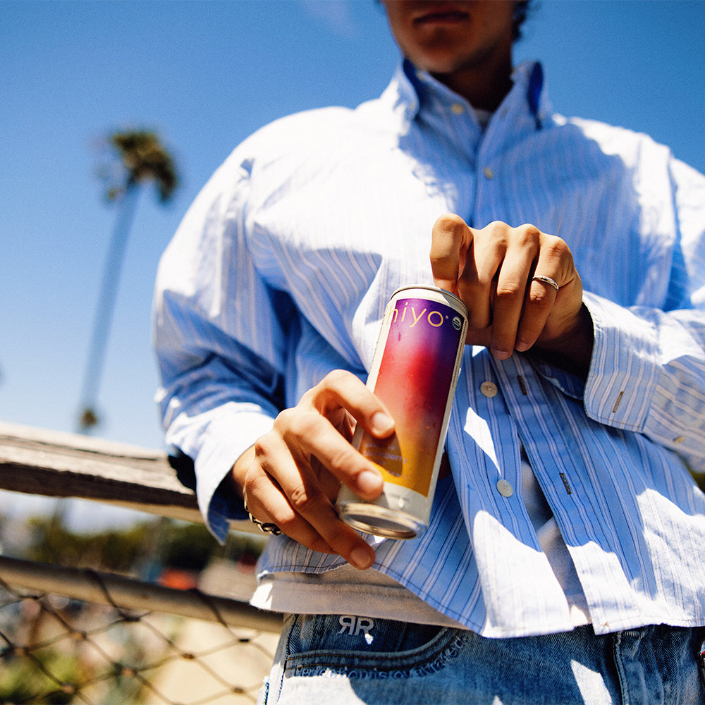 Person holding a colorful can against a blue sky background