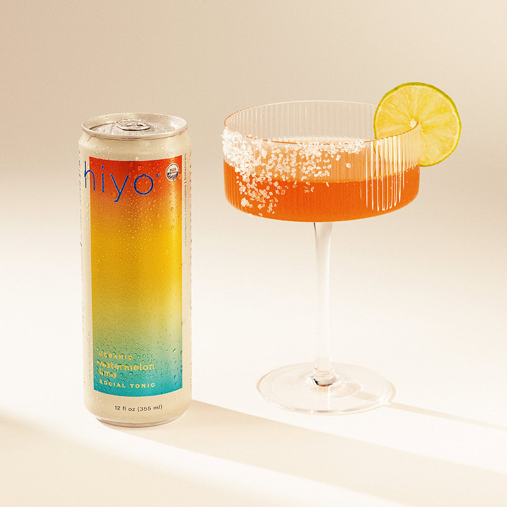 Can of hiyo sparkling lemon tonic next to a glass with a lemon wedge on a light background