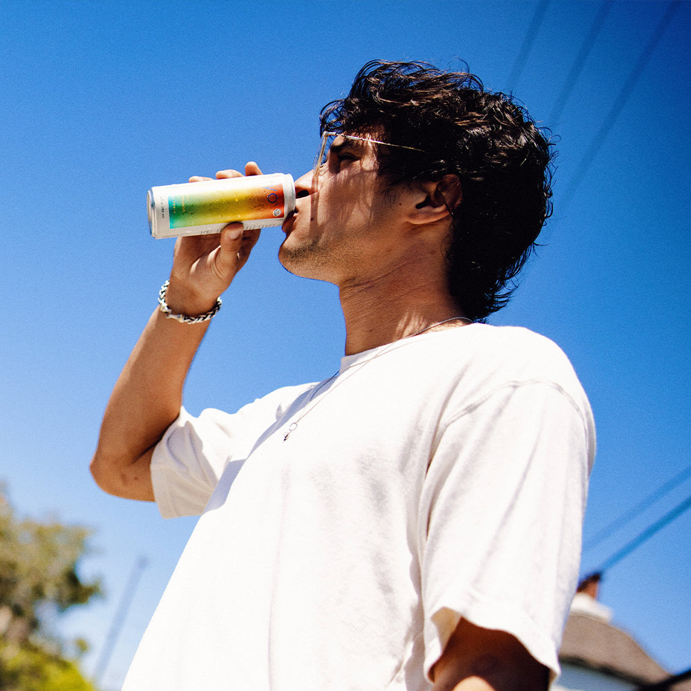 Person drinking from a colorful cup against a blue sky
