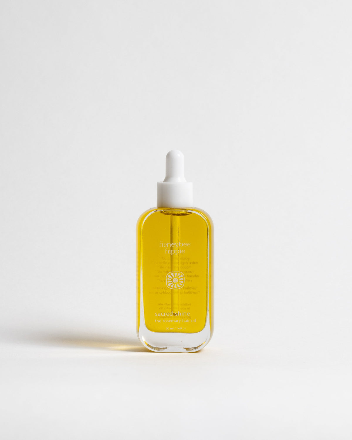 A clear glass dropper bottle filled with golden yellow liquid, featuring a white rubber dropper cap and gold text on the front, set against a seamless white background.