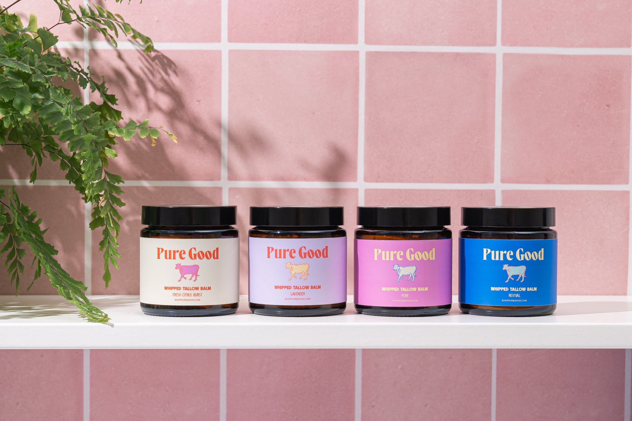 Four jars labeled 'Pure Good' on a shelf with a pink tiled wall background