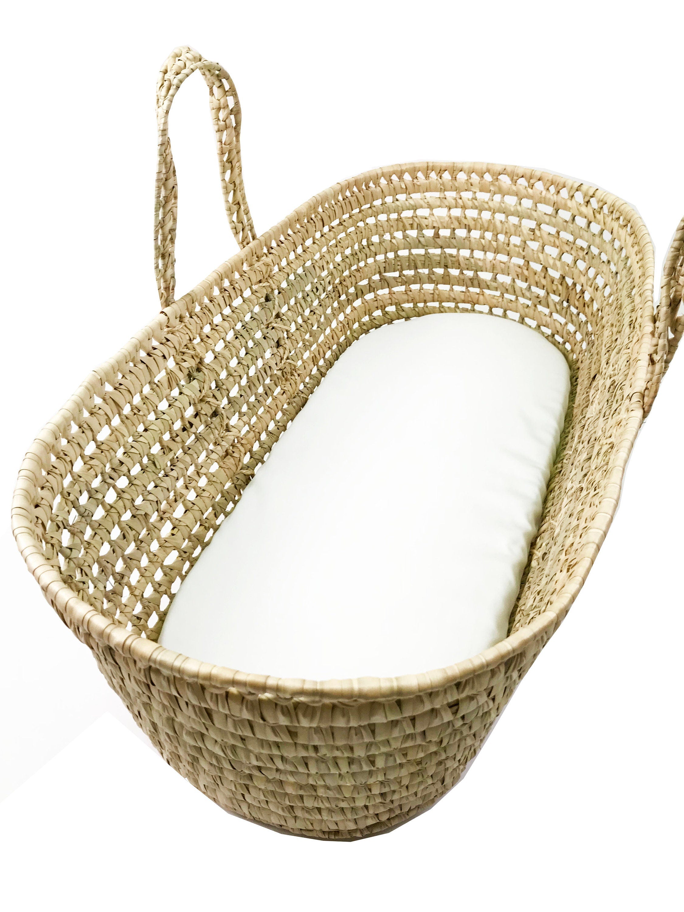 Woven baby basket with a white cushion on a white background