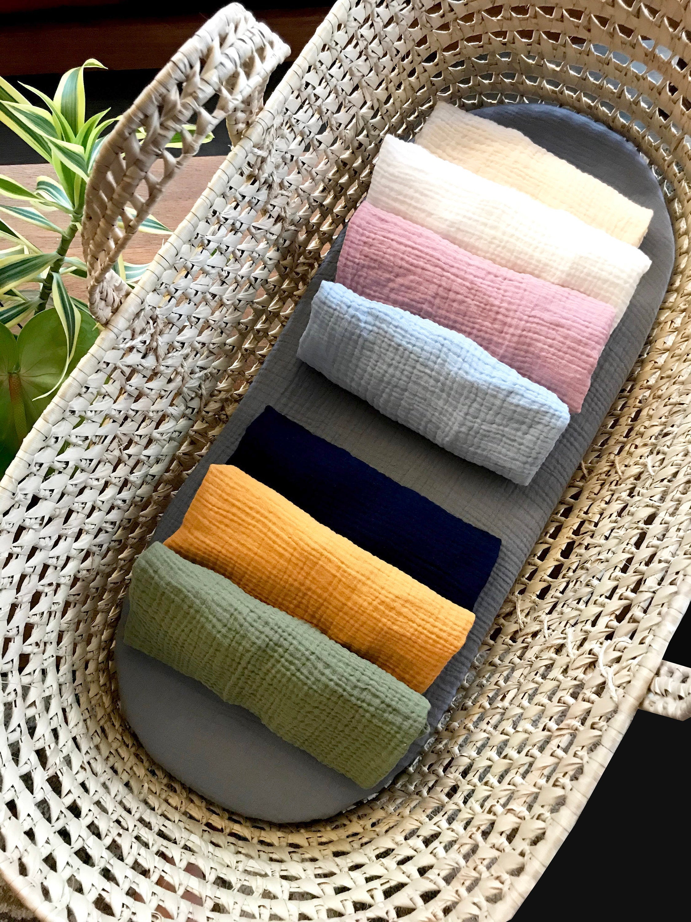 Set of colorful baby blankets in a wicker basket with a plant in the background