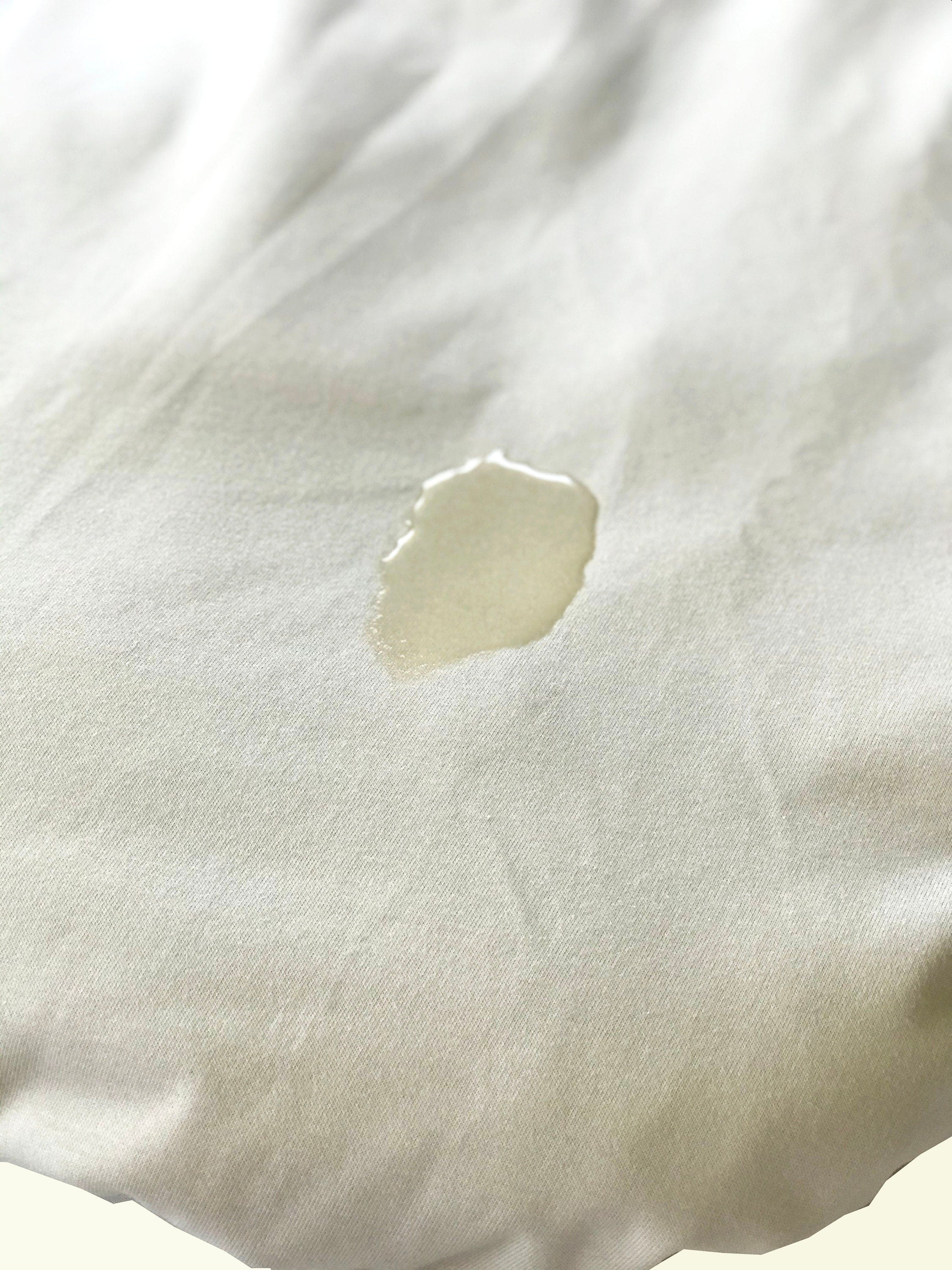 Close-up of a white fabric with a small stain on a light background