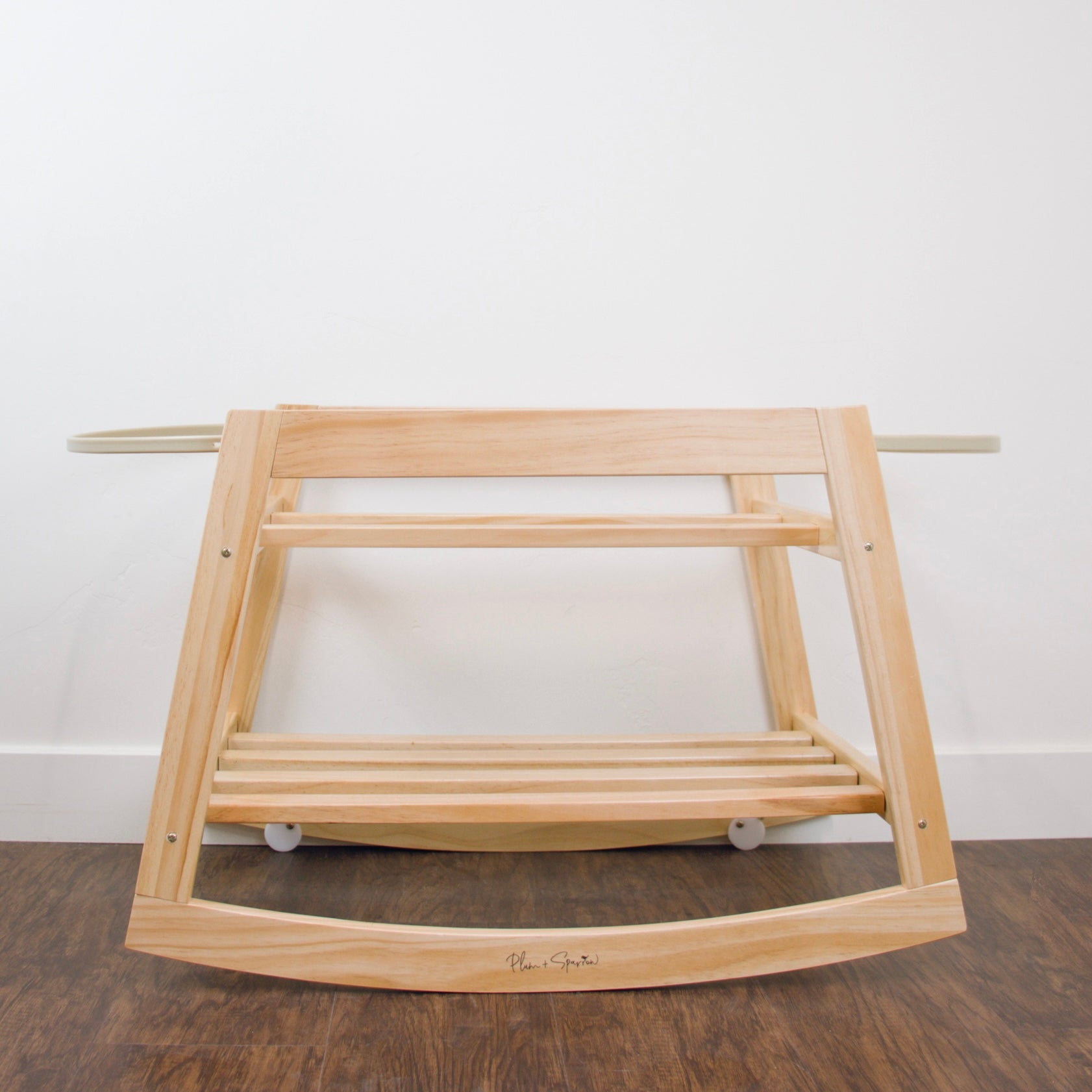 Wooden baby rocker on a wooden floor with a white wall background