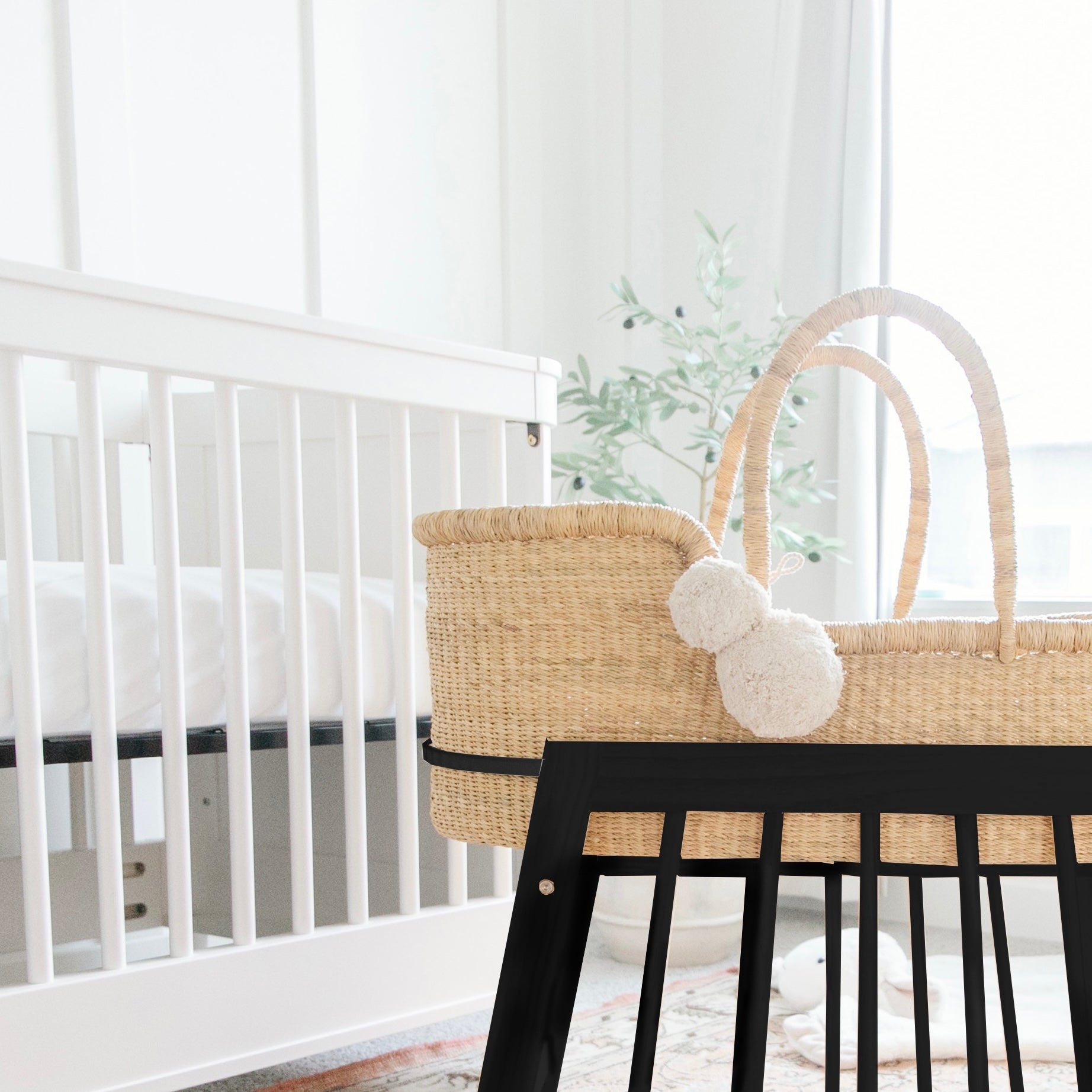 Nursery with a white crib and a wicker Moses basket with black base.
