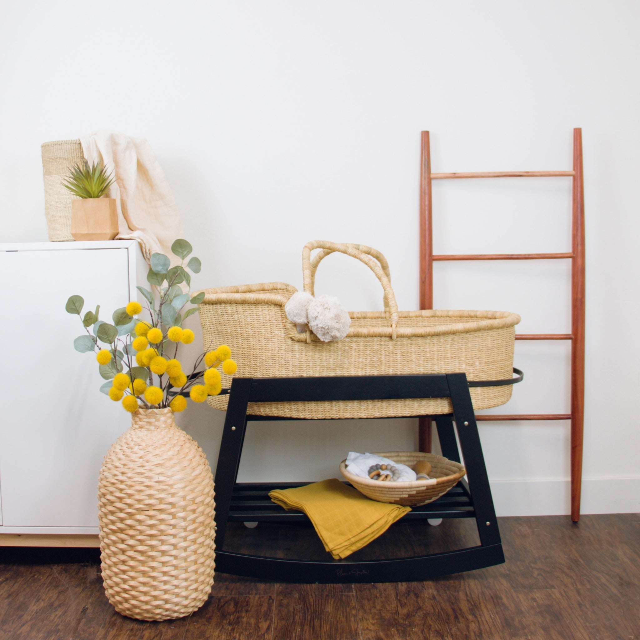 Nursery setup with a bassinet, basket, and decorative items on a wooden floor.