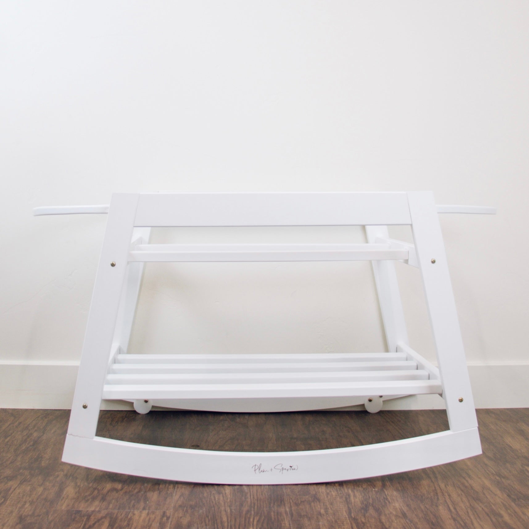White wooden rocking chair on a wooden floor with a white wall background