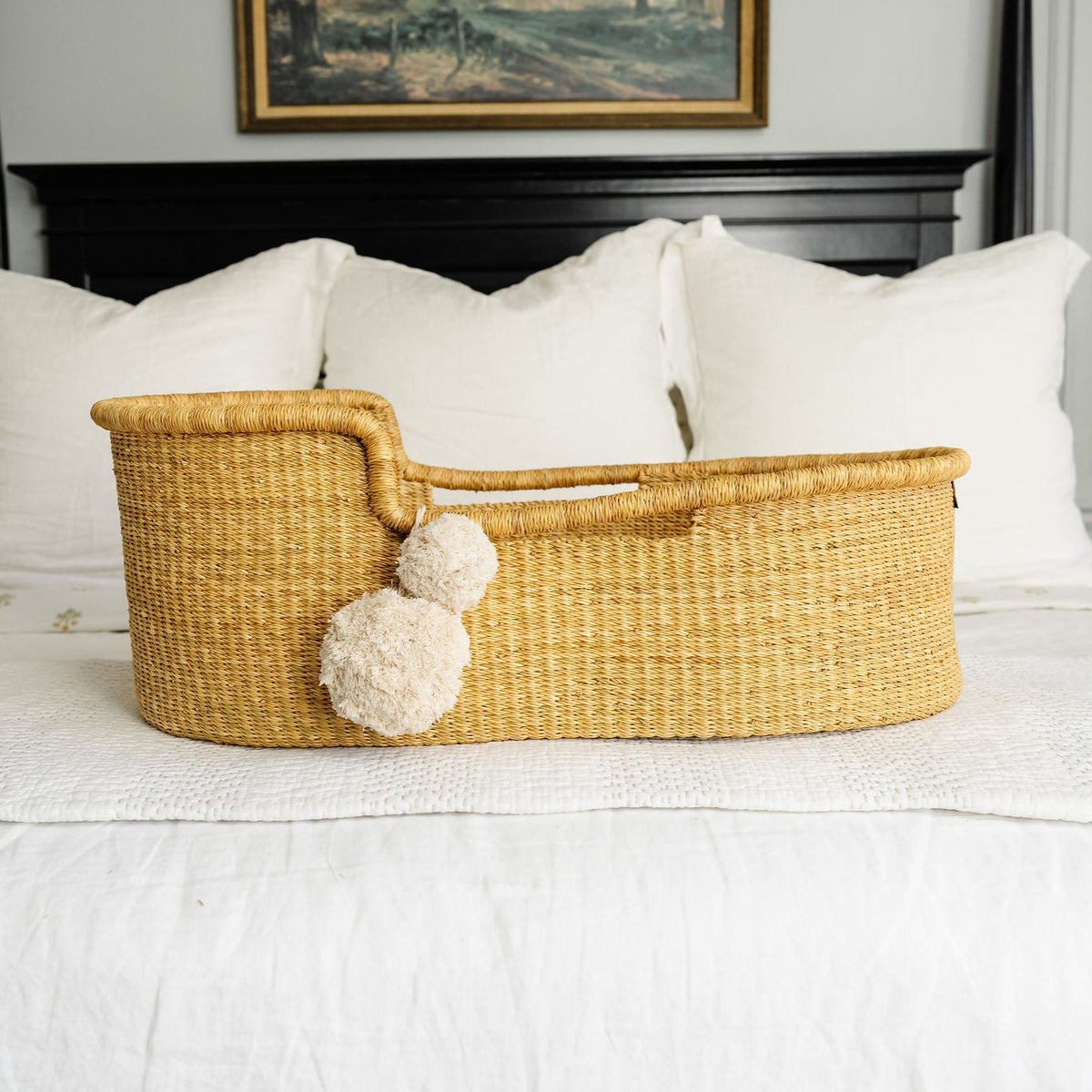 Woven basket with pom-poms on a bed