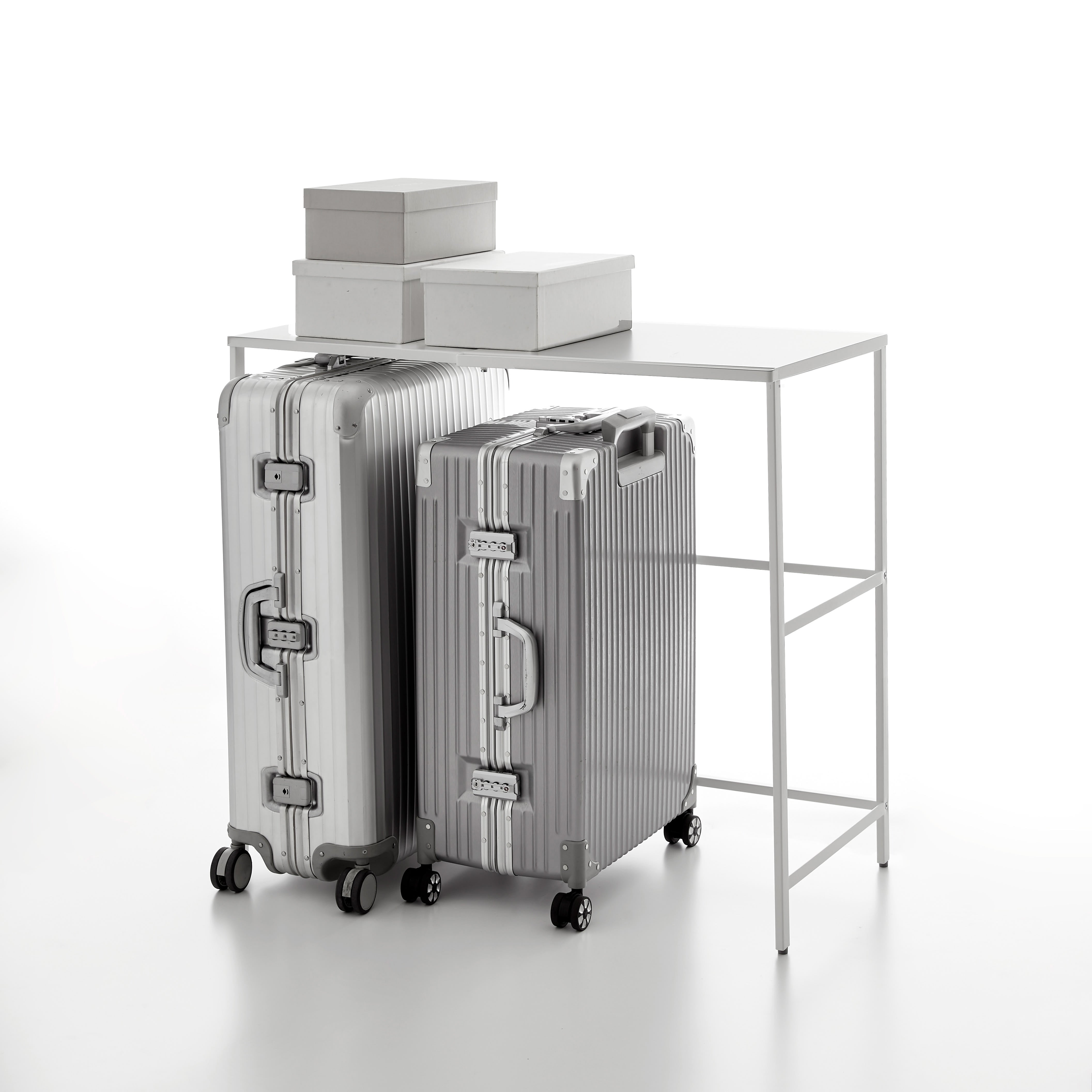 Silver suitcases on a white surface with a white table and boxes in the background