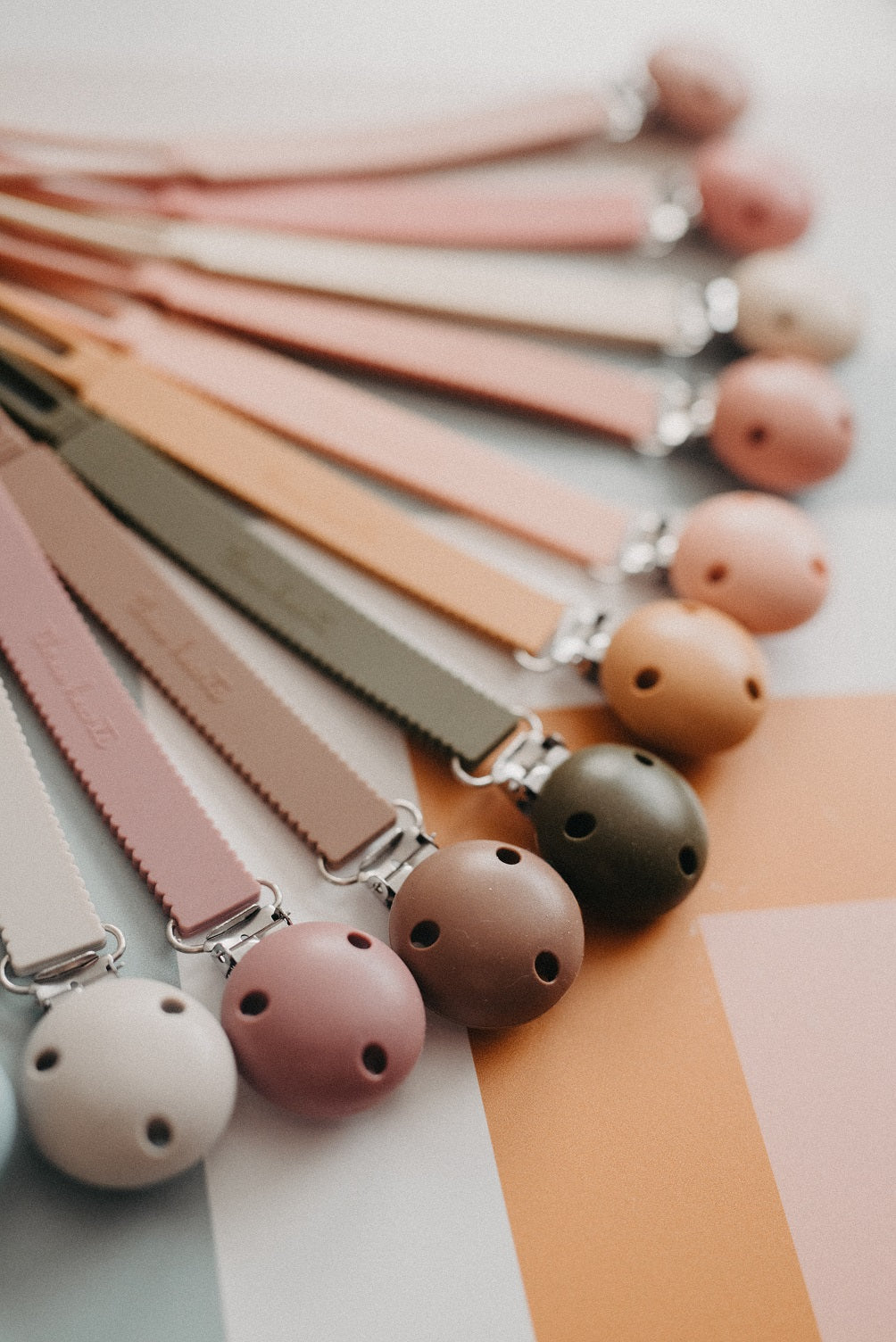 Set of colorful pacifier clips on a neutral background