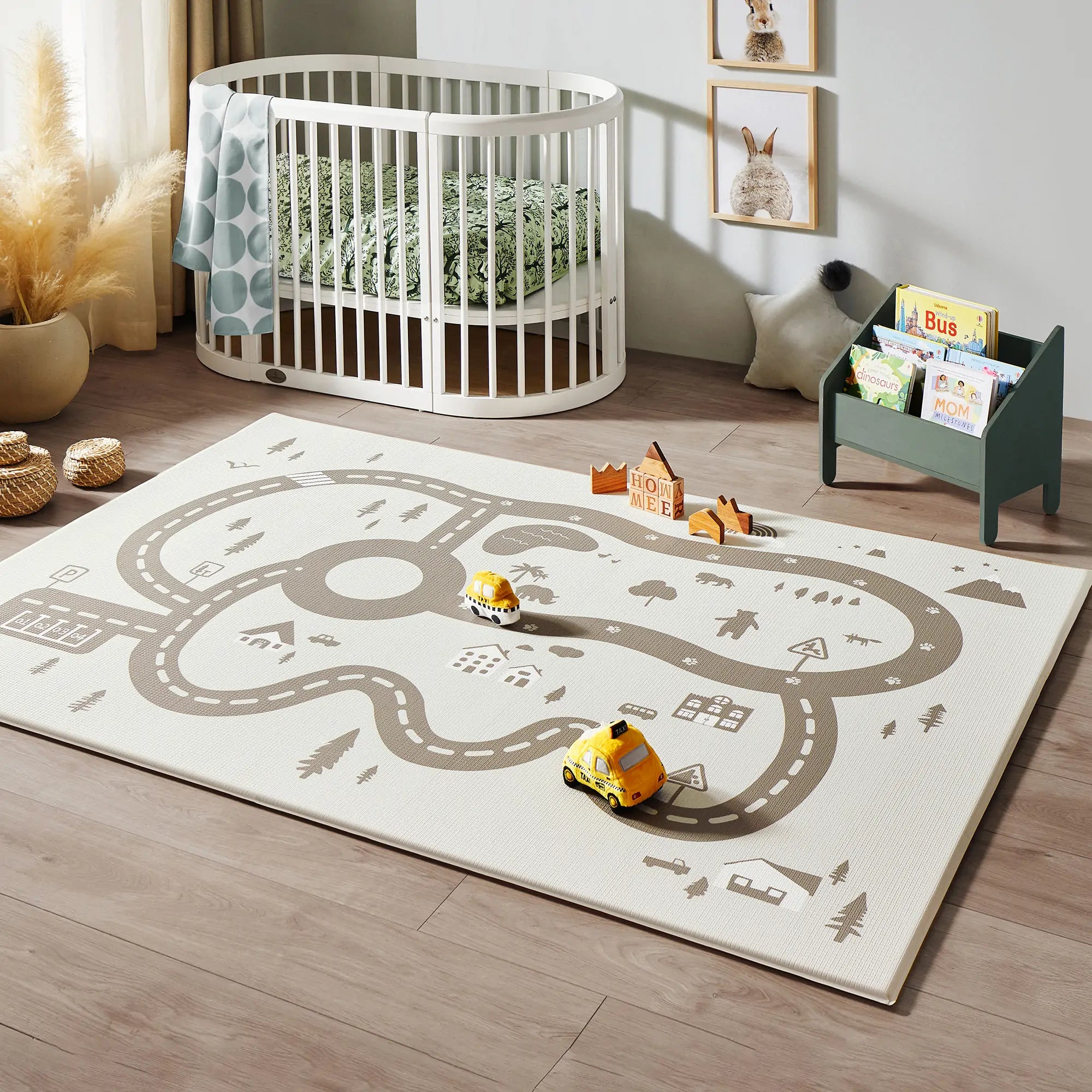 Children's room with a crib, play rug, and toys on a wooden floor.