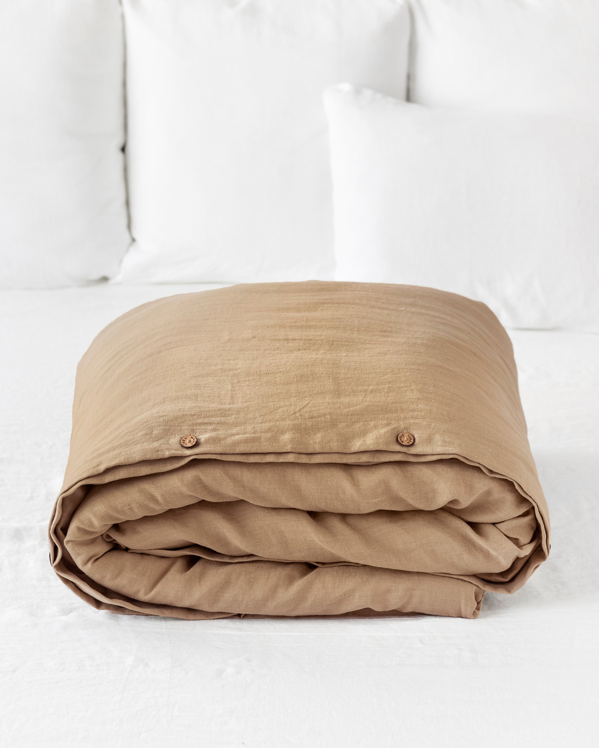 Folded beige blanket on a white bed