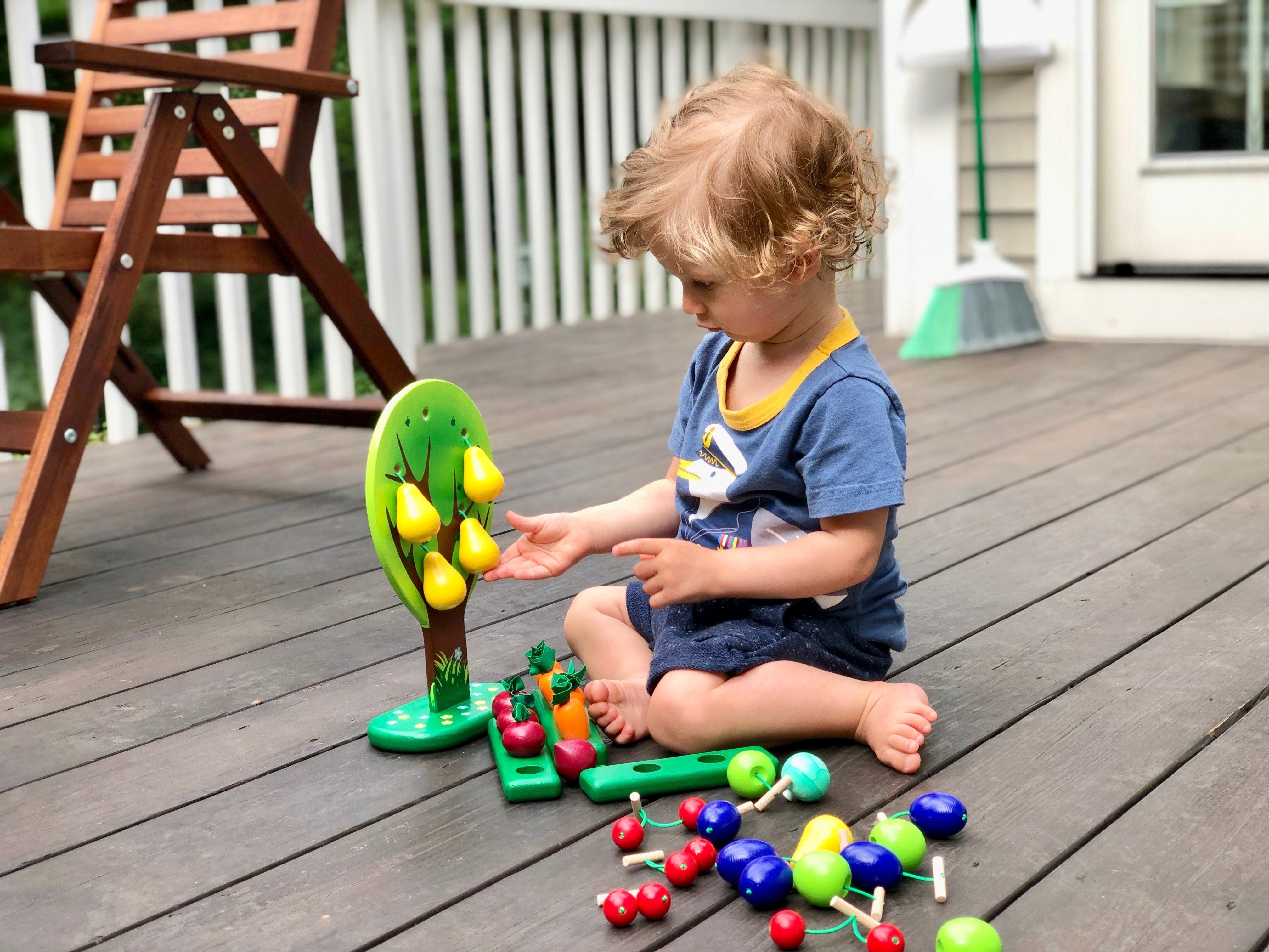 Child playing with a colorful educational toy on a wooden deck