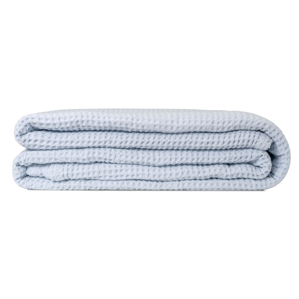 Folded light blue blanket on a white background